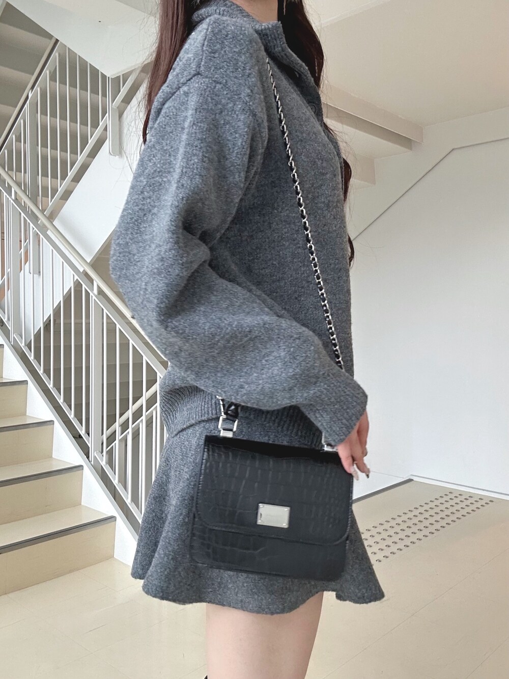 ブラック系のダウンジャケット/コート、グレー系のワンピース、ブラック系のハンドバッグを着用したレディースの秋コーディネートの7枚目の写真
