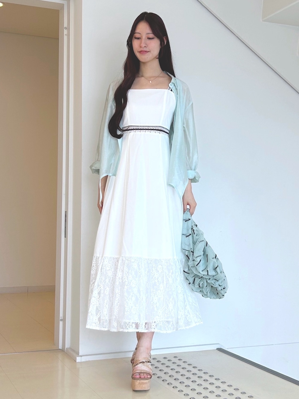 グリーン系のハンドバッグ、ホワイト系のワンピース、ブラウン系のサンダルを着用したレディースの夏コーディネートの3枚目の写真