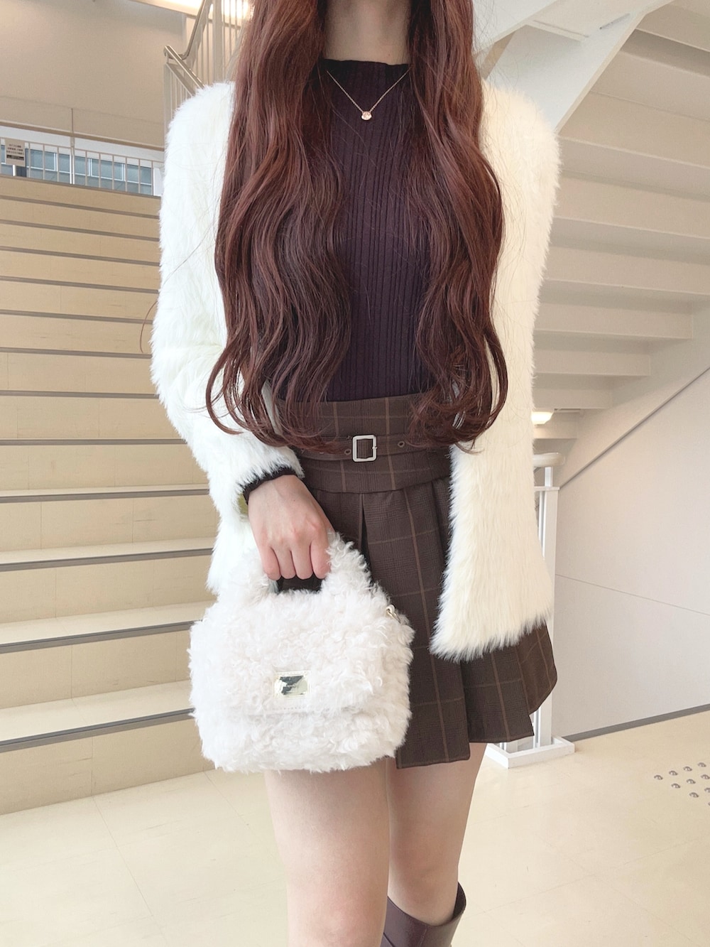 ブラウン系のスカート、レッド系のブーツ、ホワイト系のハンドバッグを着用したレディースの秋コーディネートの5枚目の写真