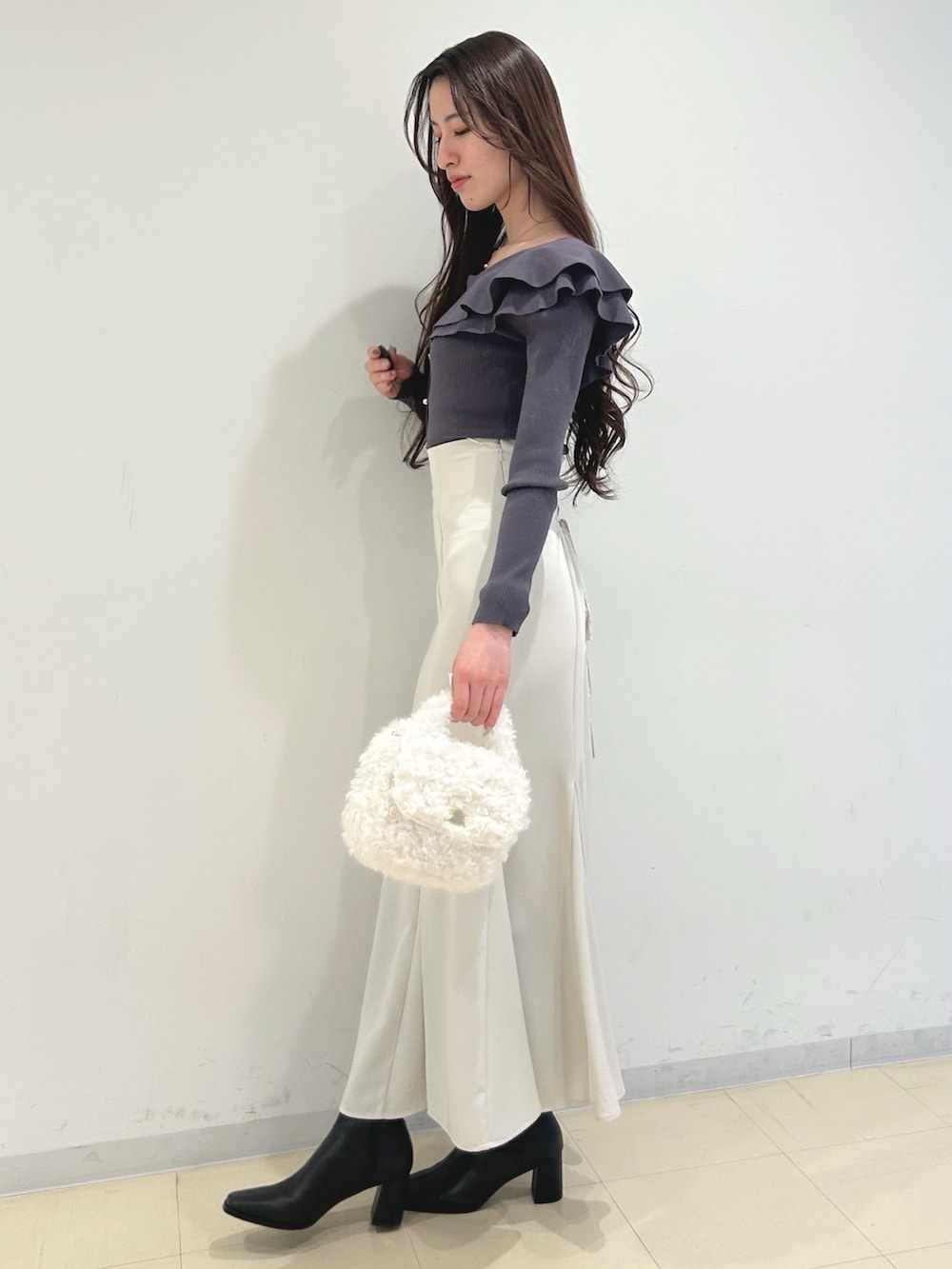 ホワイト系のスカート、ブラック系のブーツ、グレー系のニット/セーターを着用したレディースの冬コーディネートの2枚目の写真