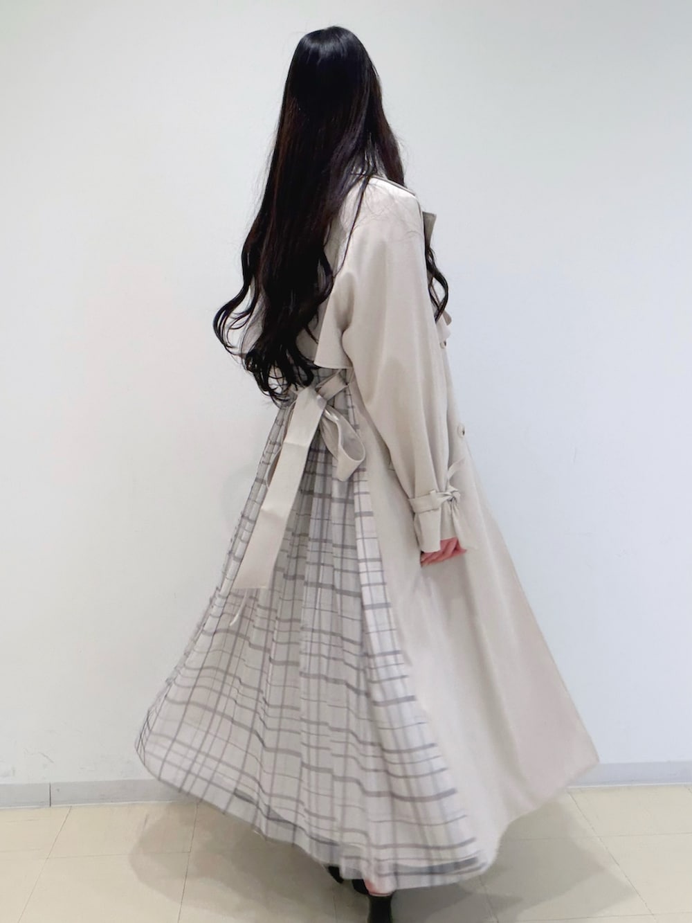 ブラック系のワンピース、ベージュ系のトレンチコート、ブラウン系のハンドバッグを着用したレディースの冬コーディネートの6枚目の写真