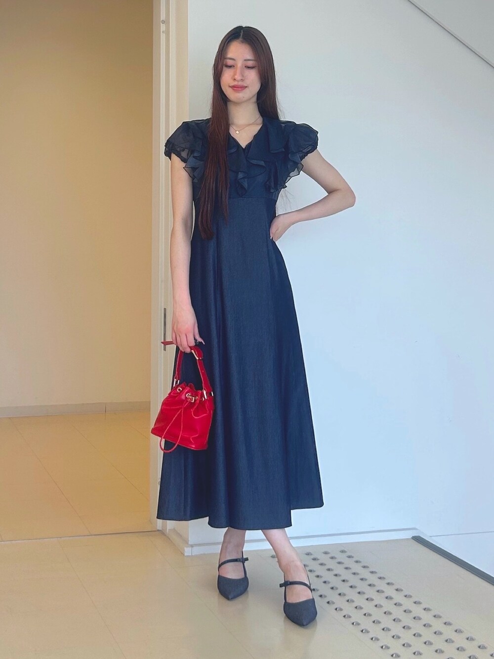 ブルー系のワンピース、レッド系のハンドバッグ、ブルー系のパンプスを着用したレディースの夏コーディネートの3枚目の写真