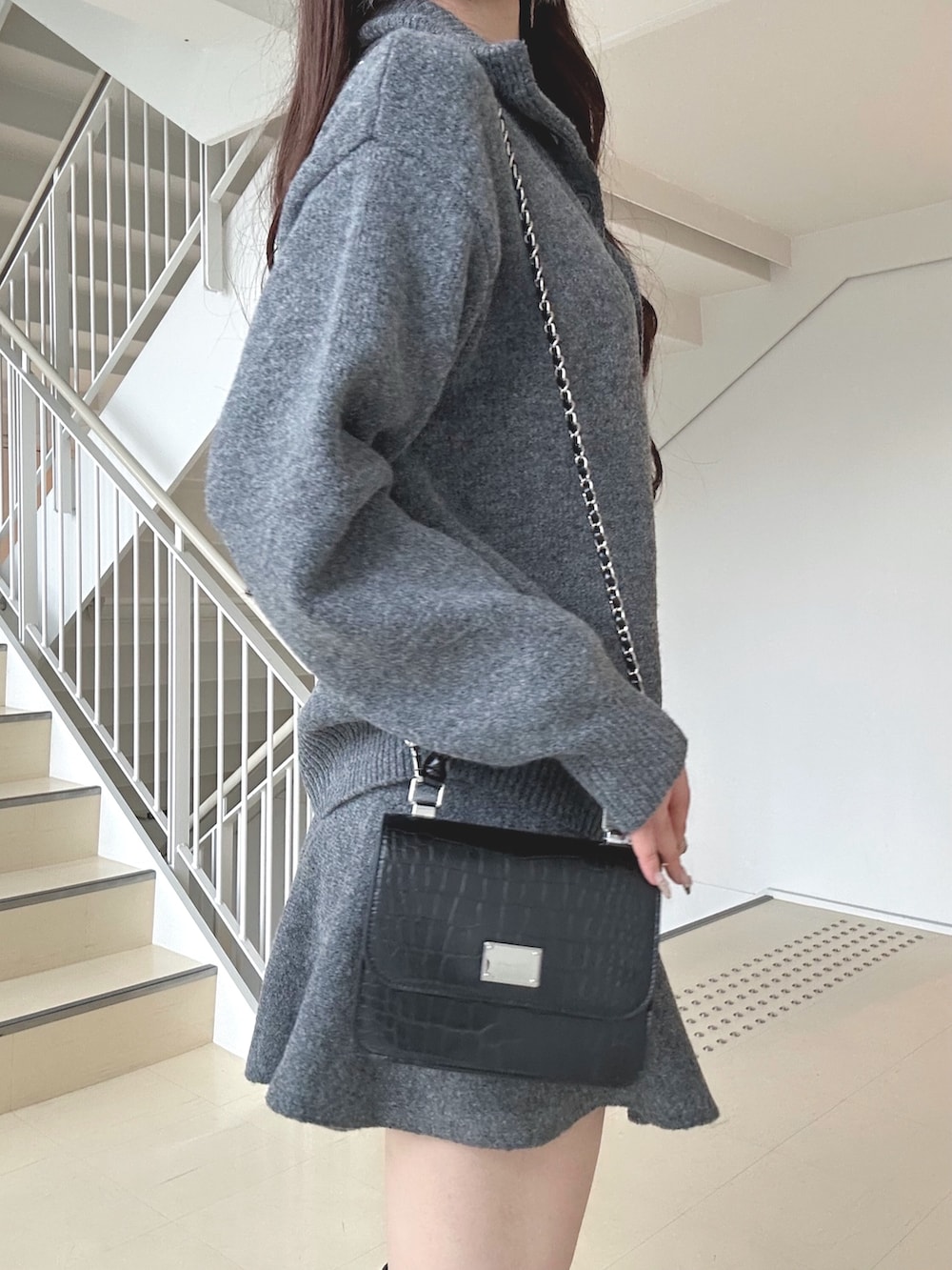 グレー系のワンピース、ブラック系のブーツ、ブラック系のハンドバッグを着用したレディースの秋コーディネートの6枚目の写真