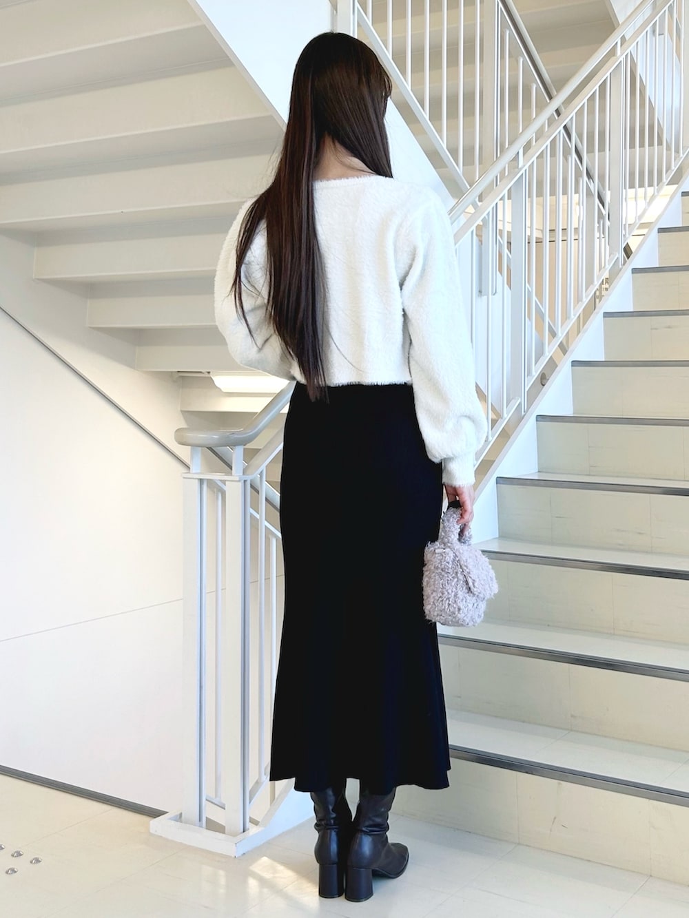 ブラック系のワンピース、ブラック系のキャミソール、ホワイト系のカーディガン/ボレロを着用したレディースの冬コーディネートの3枚目の写真