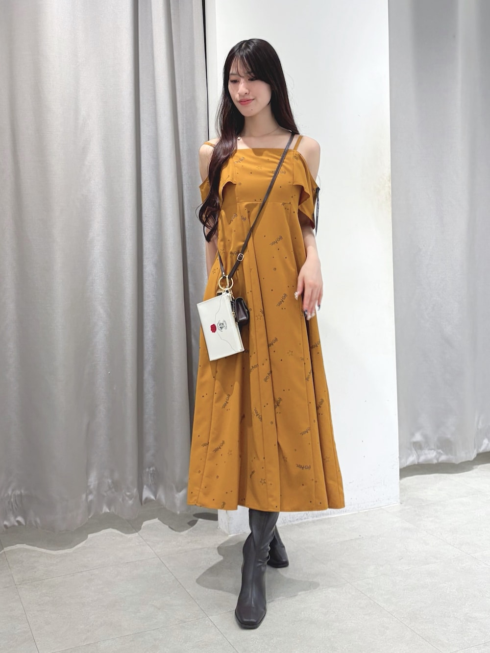 イエロー系のワンピース、ブラウン系のショルダーバッグ、ブラウン系のブーツを着用したレディースの夏コーディネートの3枚目の写真