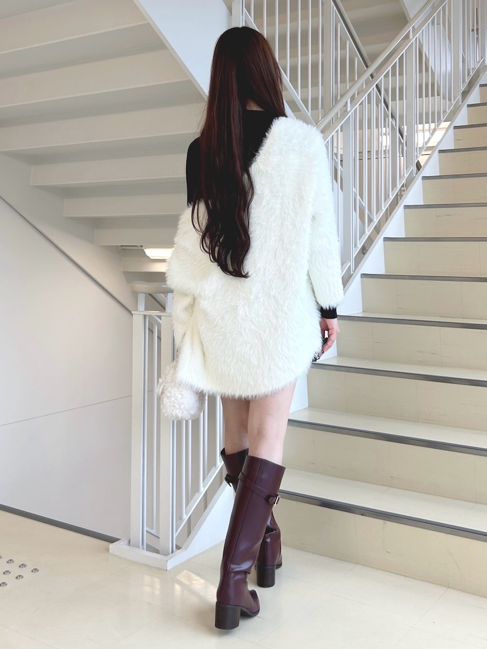 ブラウン系のスカート、レッド系のブーツ、ホワイト系のハンドバッグを着用したレディースの秋コーディネートの4枚目の写真