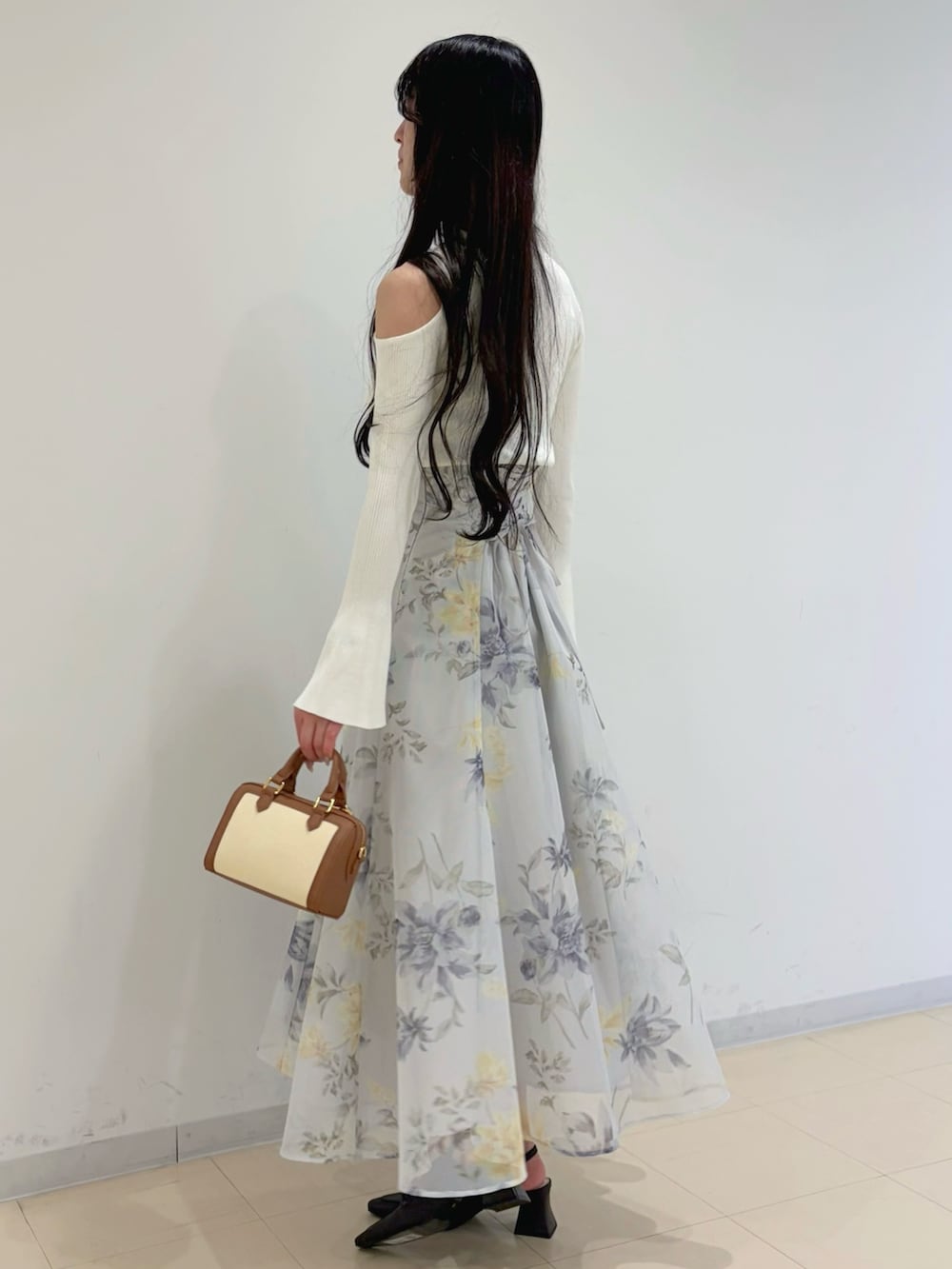 ホワイト系のニット/セーター、ブラウン系のハンドバッグ、グリーン系のスカートを着用したレディースの冬コーディネートの3枚目の写真