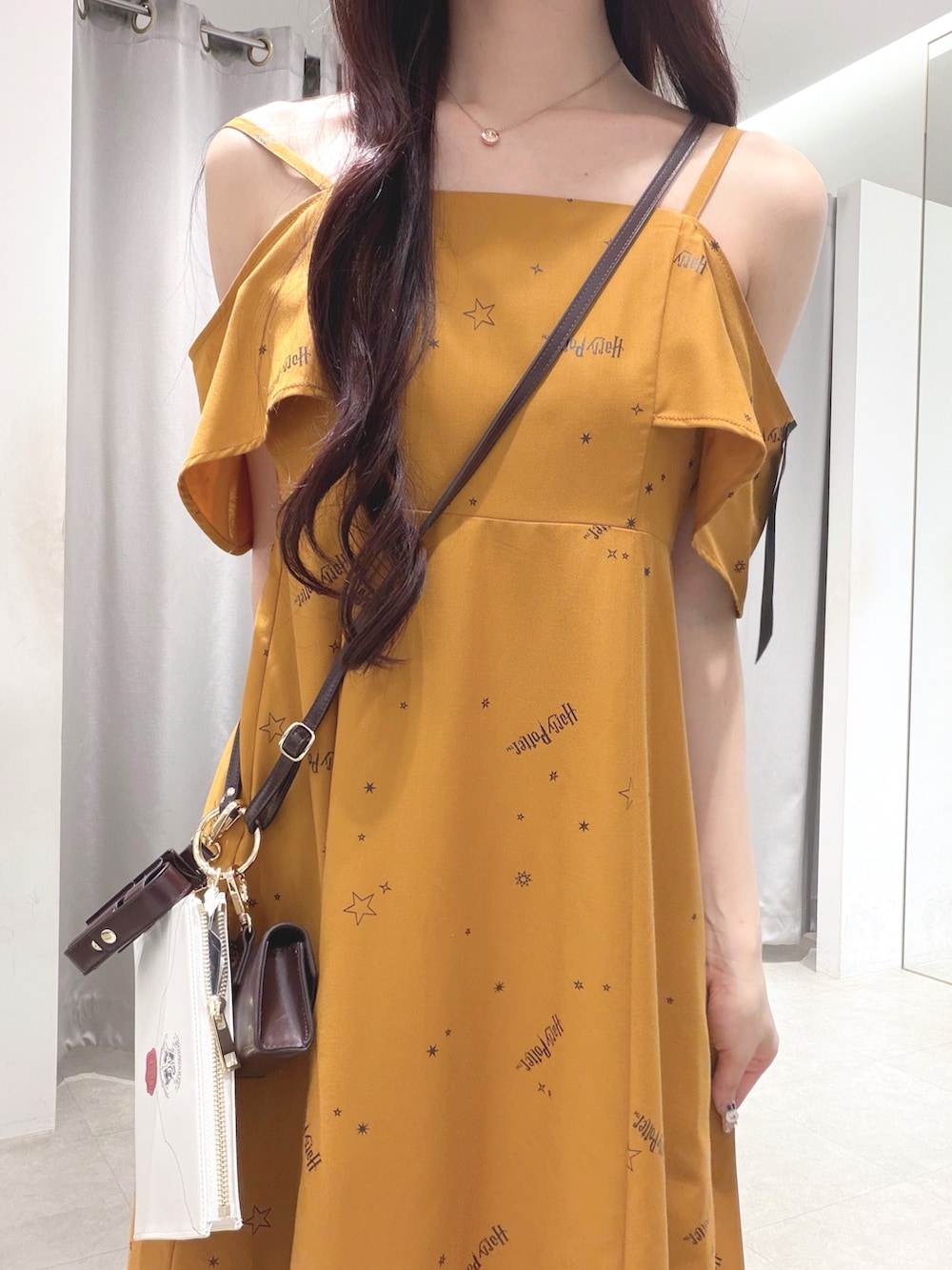 イエロー系のワンピース、ブラウン系のショルダーバッグ、ブラウン系のブーツを着用したレディースの夏コーディネートの5枚目の写真