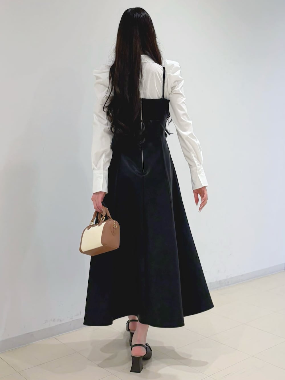 ブラック系のワンピース、ベージュ系のトレンチコート、ブラウン系のハンドバッグを着用したレディースの冬コーディネートの5枚目の写真