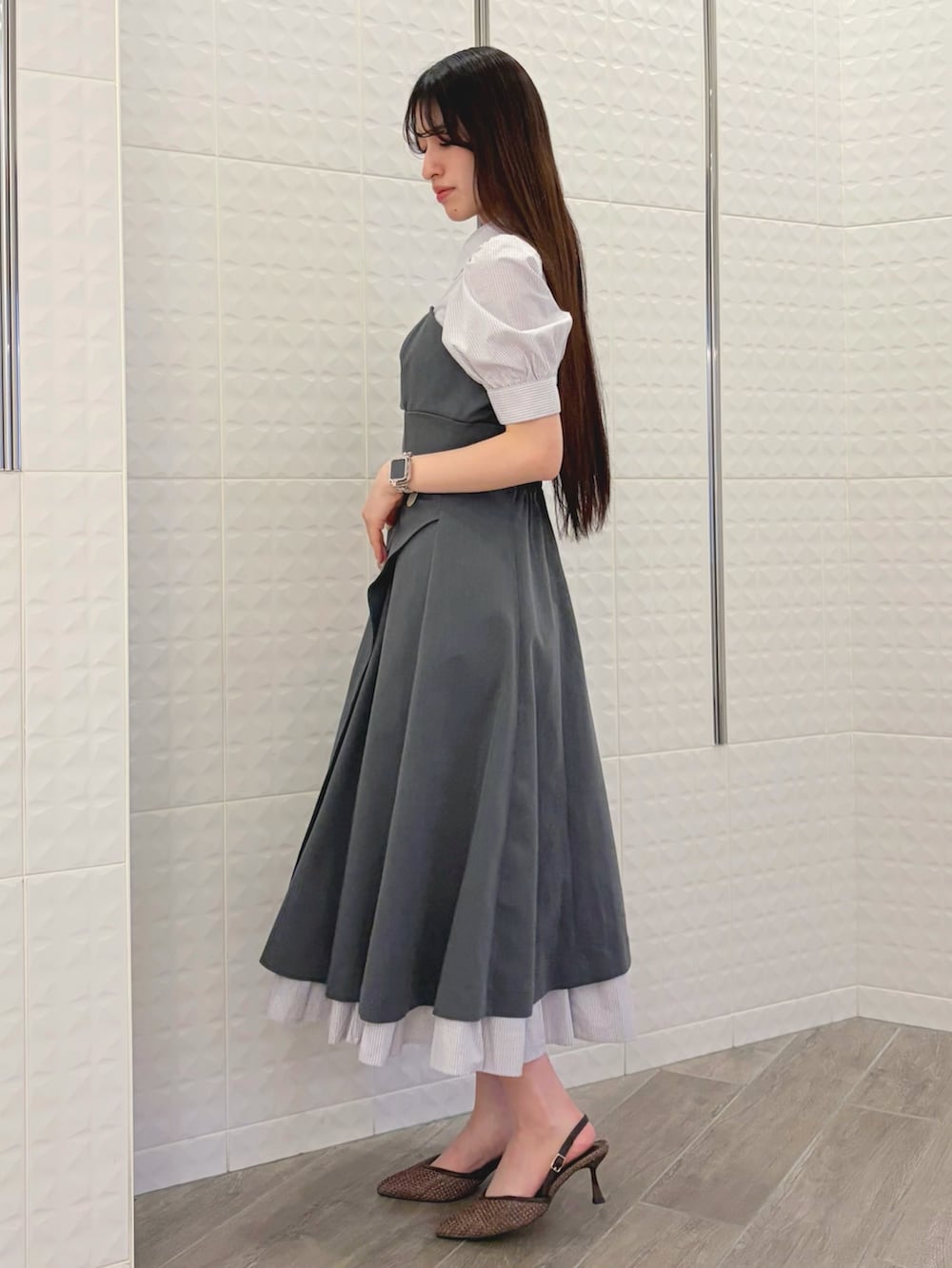 グレー系のワンピース、ホワイト系のハンドバッグ、ブラウン系のパンプスを着用したレディースの春コーディネートの2枚目の写真