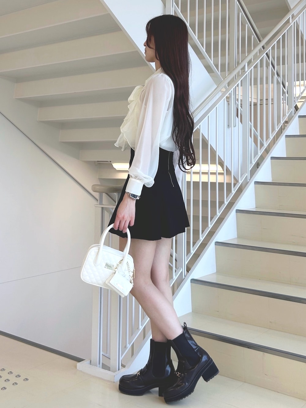 ホワイト系のシャツ/ブラウス、ブラック系のスカート、ブラウン系のブーツを着用したレディースの秋コーディネートの2枚目の写真