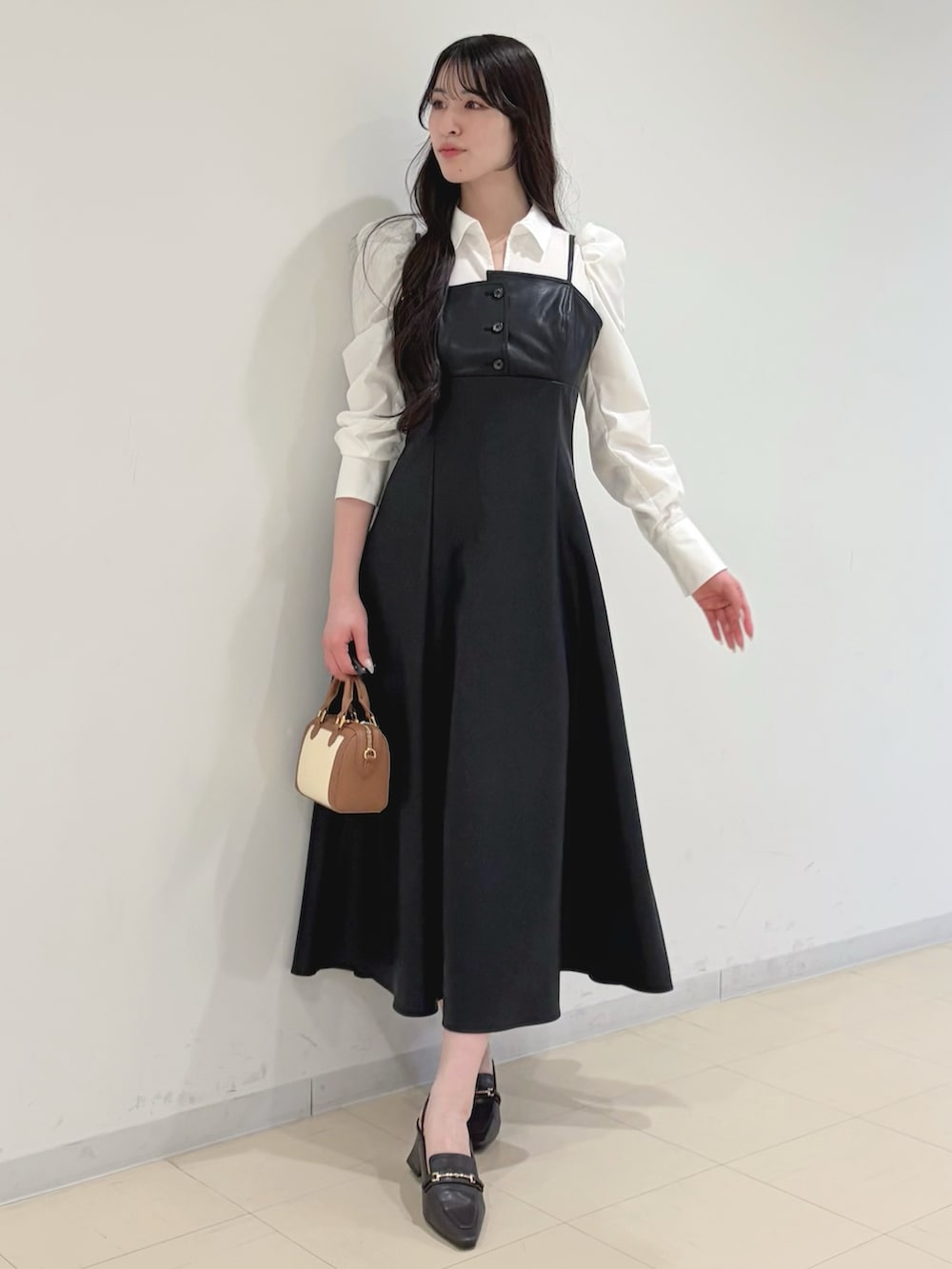 ブラック系のワンピース、ベージュ系のトレンチコート、ブラウン系のハンドバッグを着用したレディースの冬コーディネートの2枚目の写真