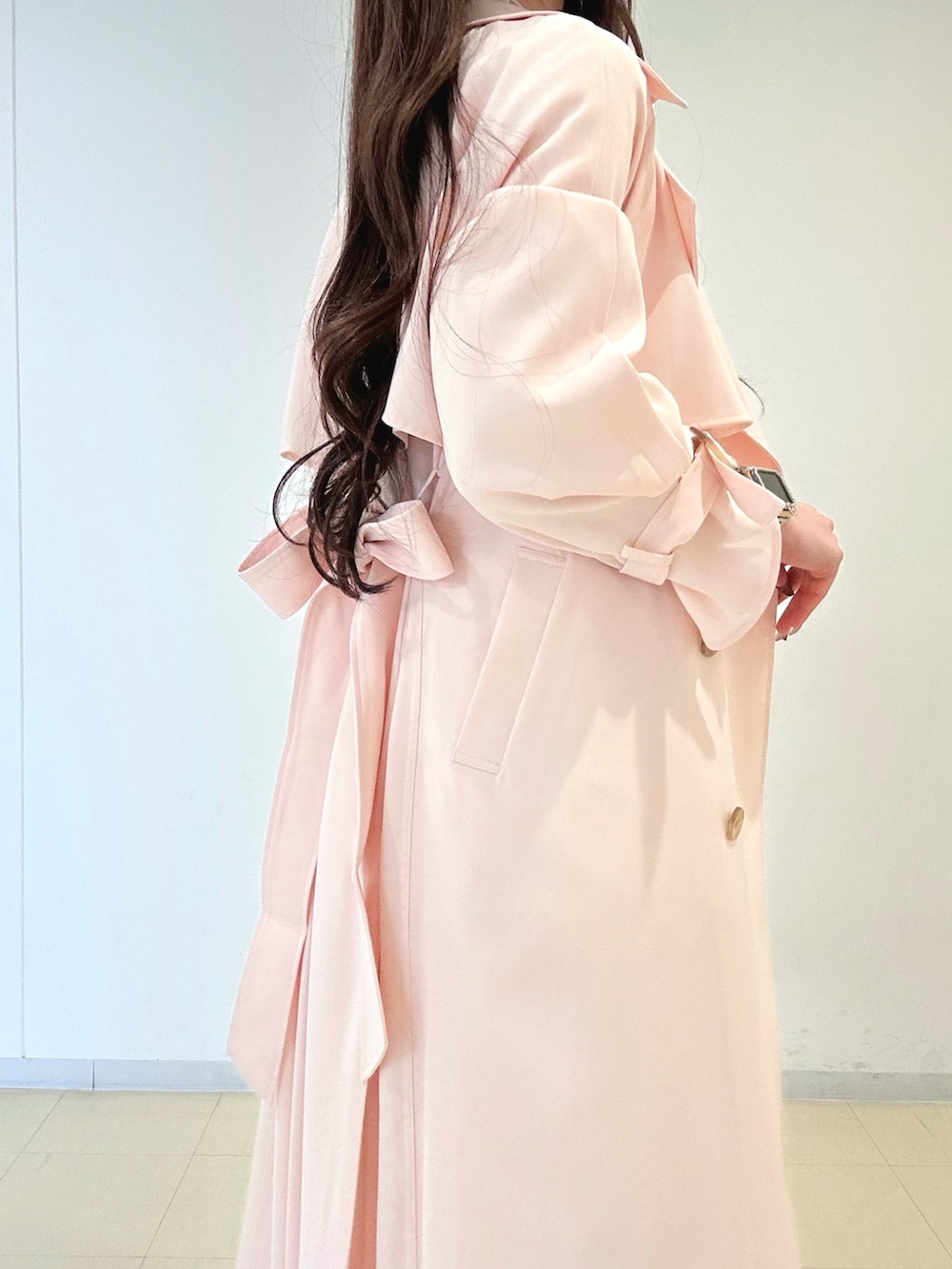 ホワイト系のワンピース、ピンク系のトレンチコート、ゴールド系のショルダーバッグを着用したレディースの冬コーディネートの5枚目の写真