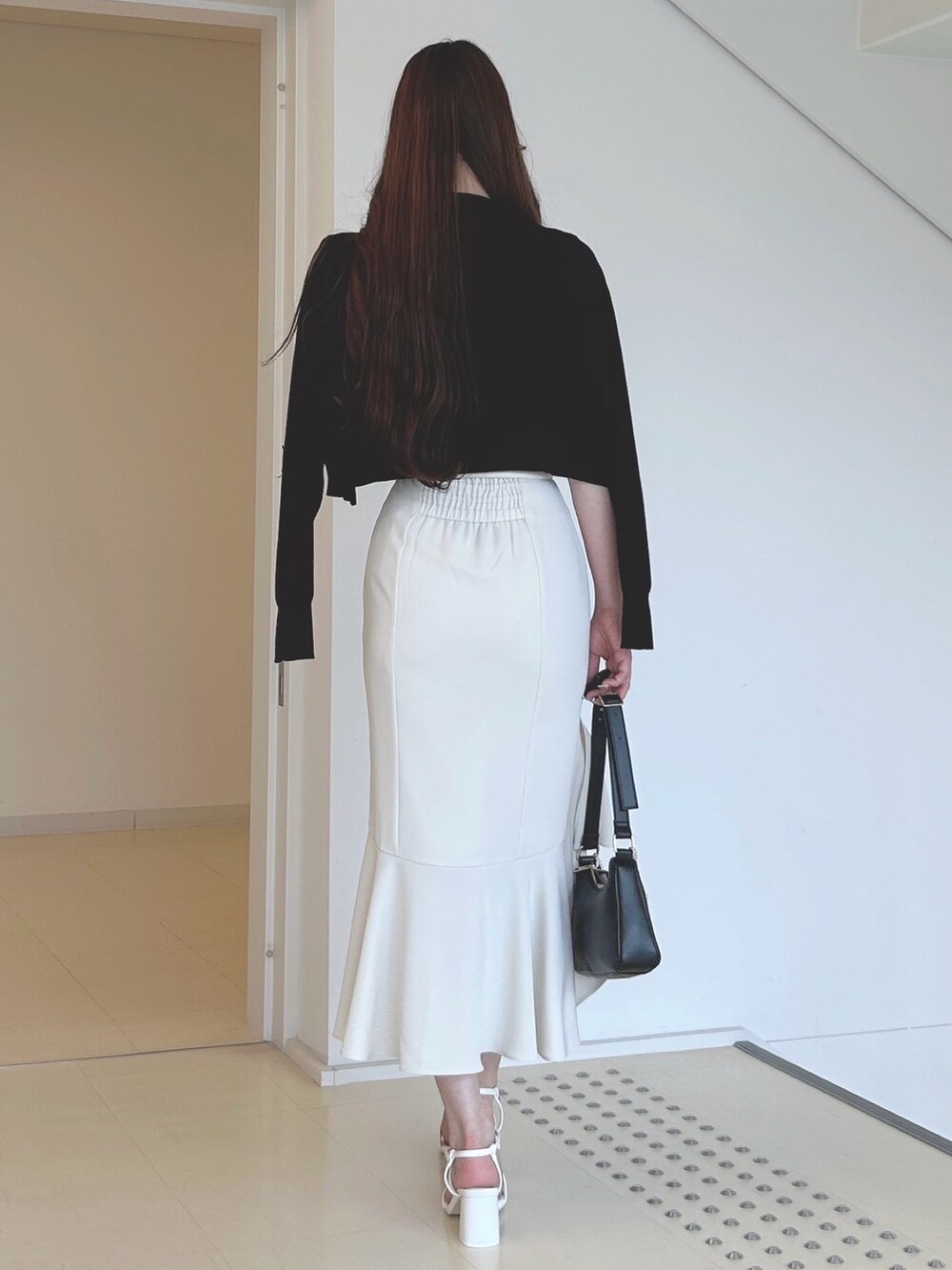 ブラック系のハンドバッグ、ホワイト系のスカート、ホワイト系のサンダルを着用したレディースの夏コーディネートの4枚目の写真