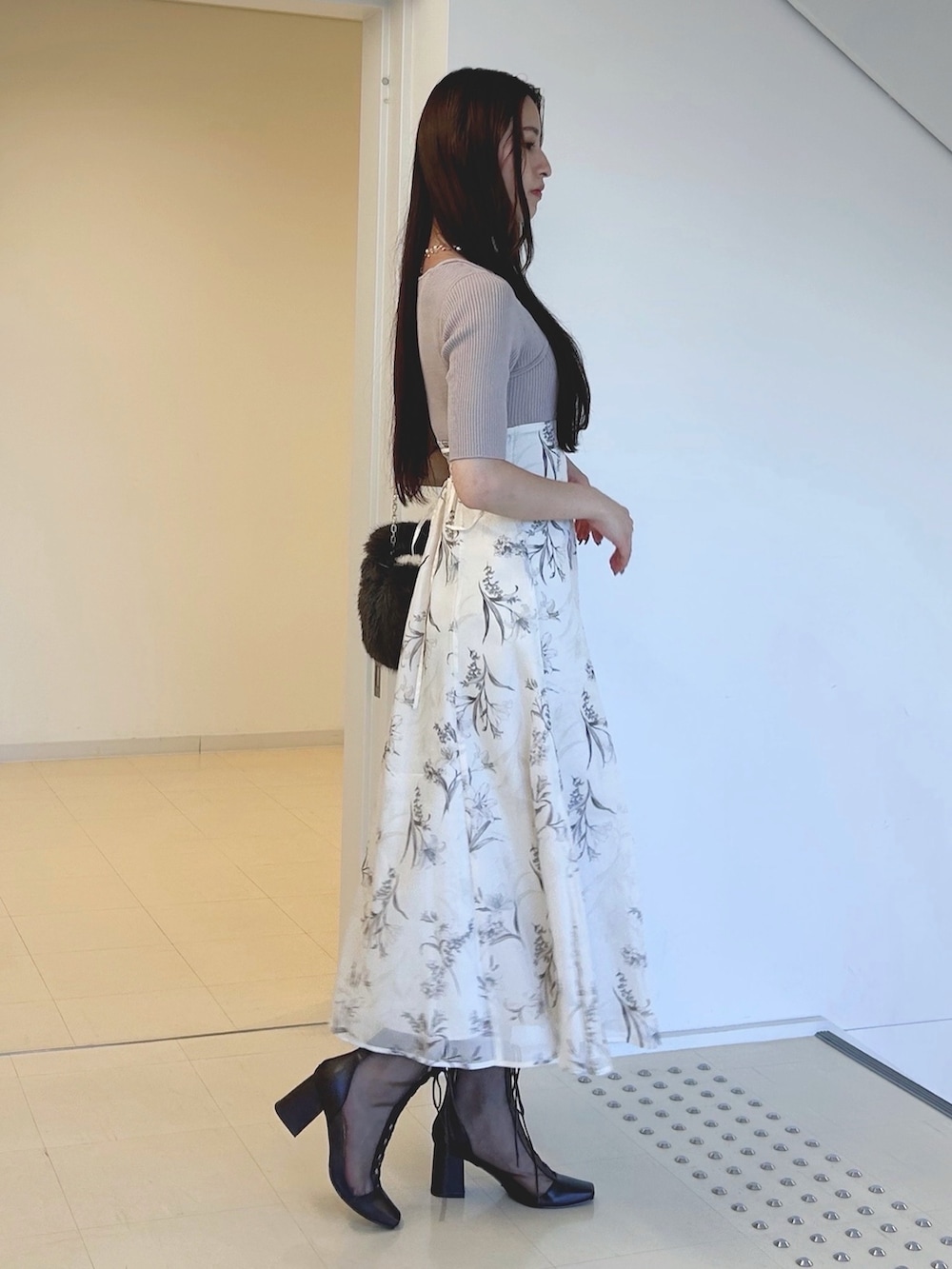 ベージュ系のワンピース、ホワイト系のカーディガン/ボレロ、ブラウン系のハンドバッグを着用したレディースの秋コーディネートの2枚目の写真