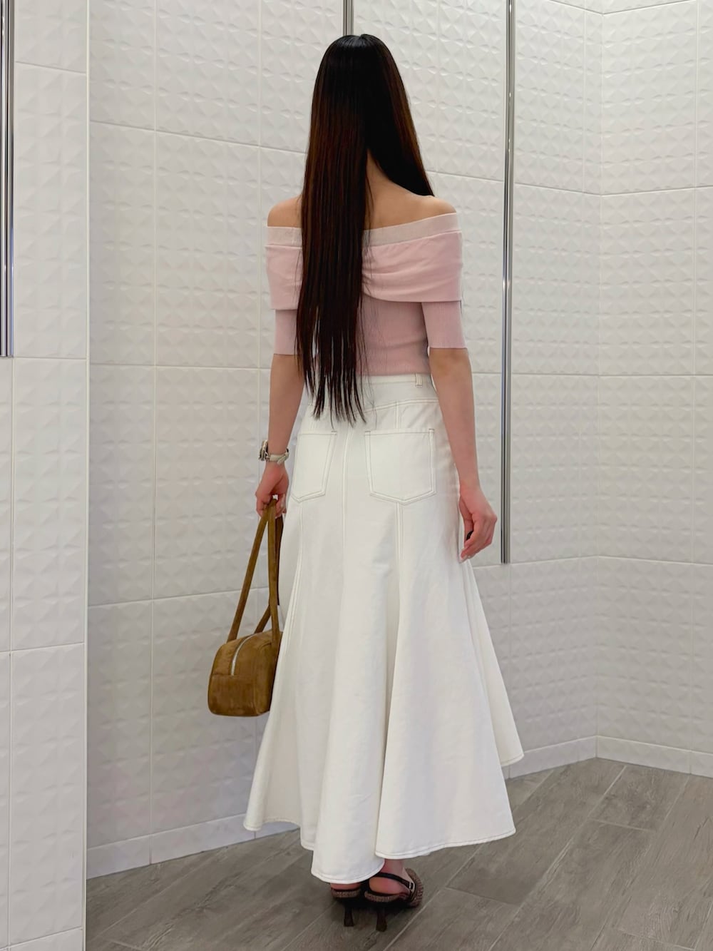 ホワイト系のスカート、ブラウン系のハンドバッグ、ブラウン系のパンプスを着用したレディースの春コーディネートの3枚目の写真