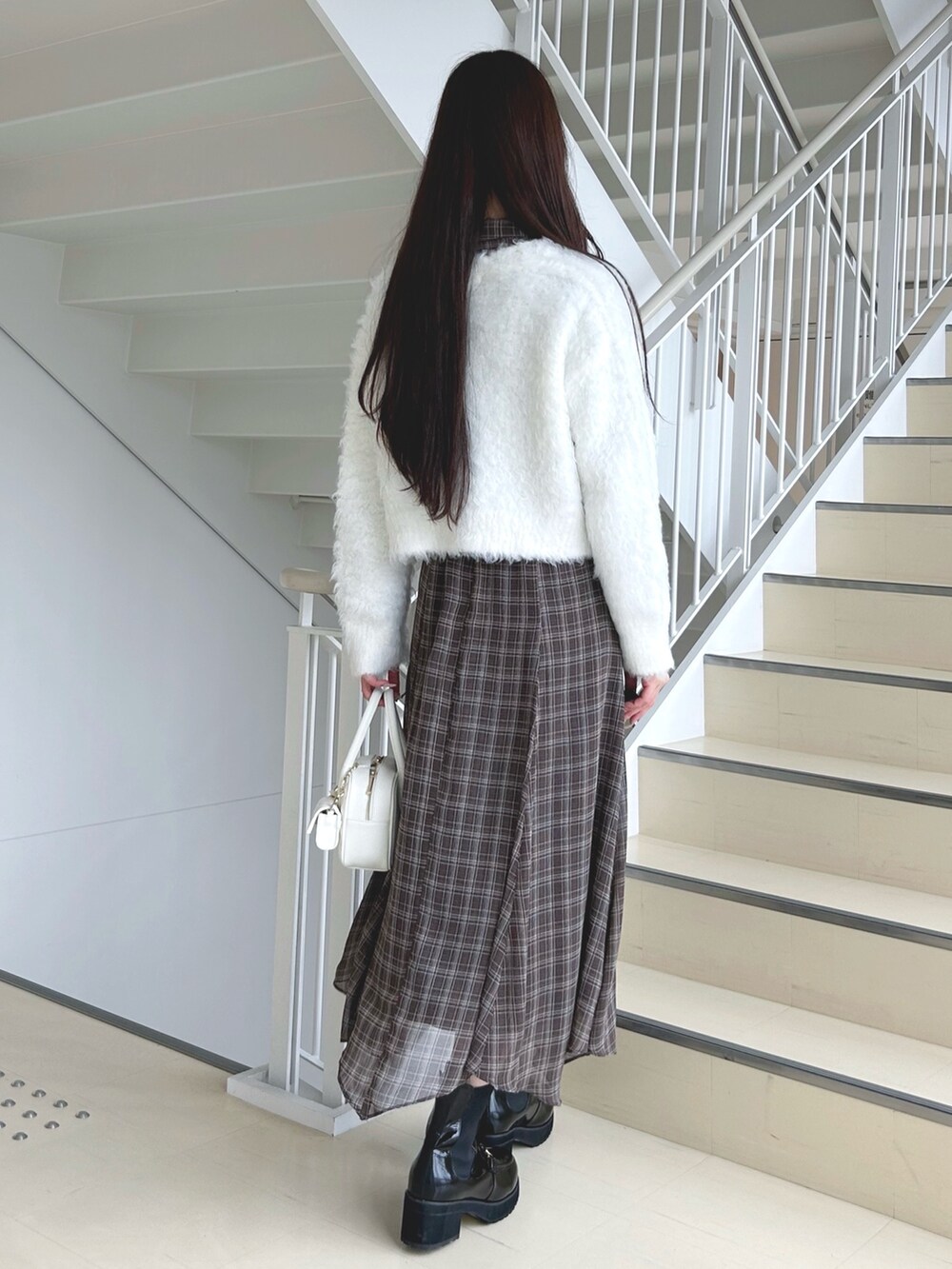 ブラウン系のワンピース、ホワイト系のハンドバッグ、ブラック系のブーツを着用したレディースの秋コーディネートの4枚目の写真