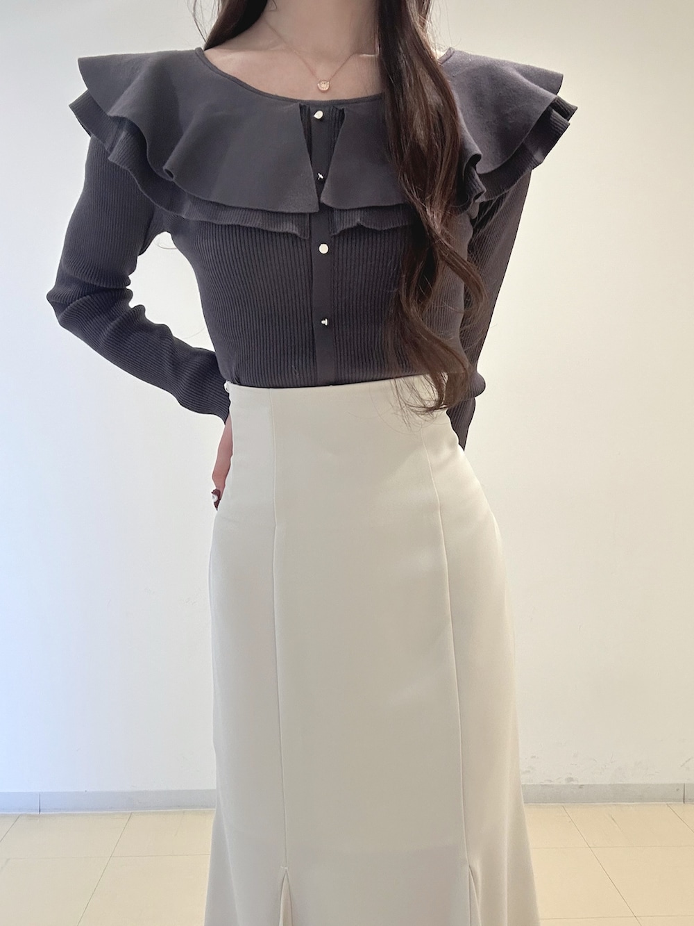 ホワイト系のスカート、ブラック系のブーツ、グレー系のニット/セーターを着用したレディースの冬コーディネートの5枚目の写真