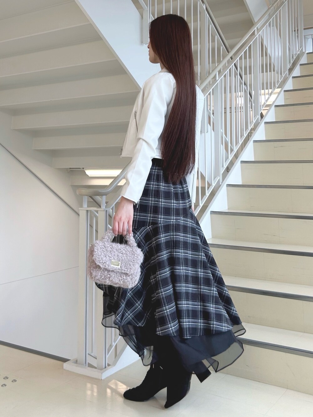 ブラック系のブーツ、ブラック系のスカート、ピンク系のハンドバッグを着用したレディースの秋コーディネートの2枚目の写真