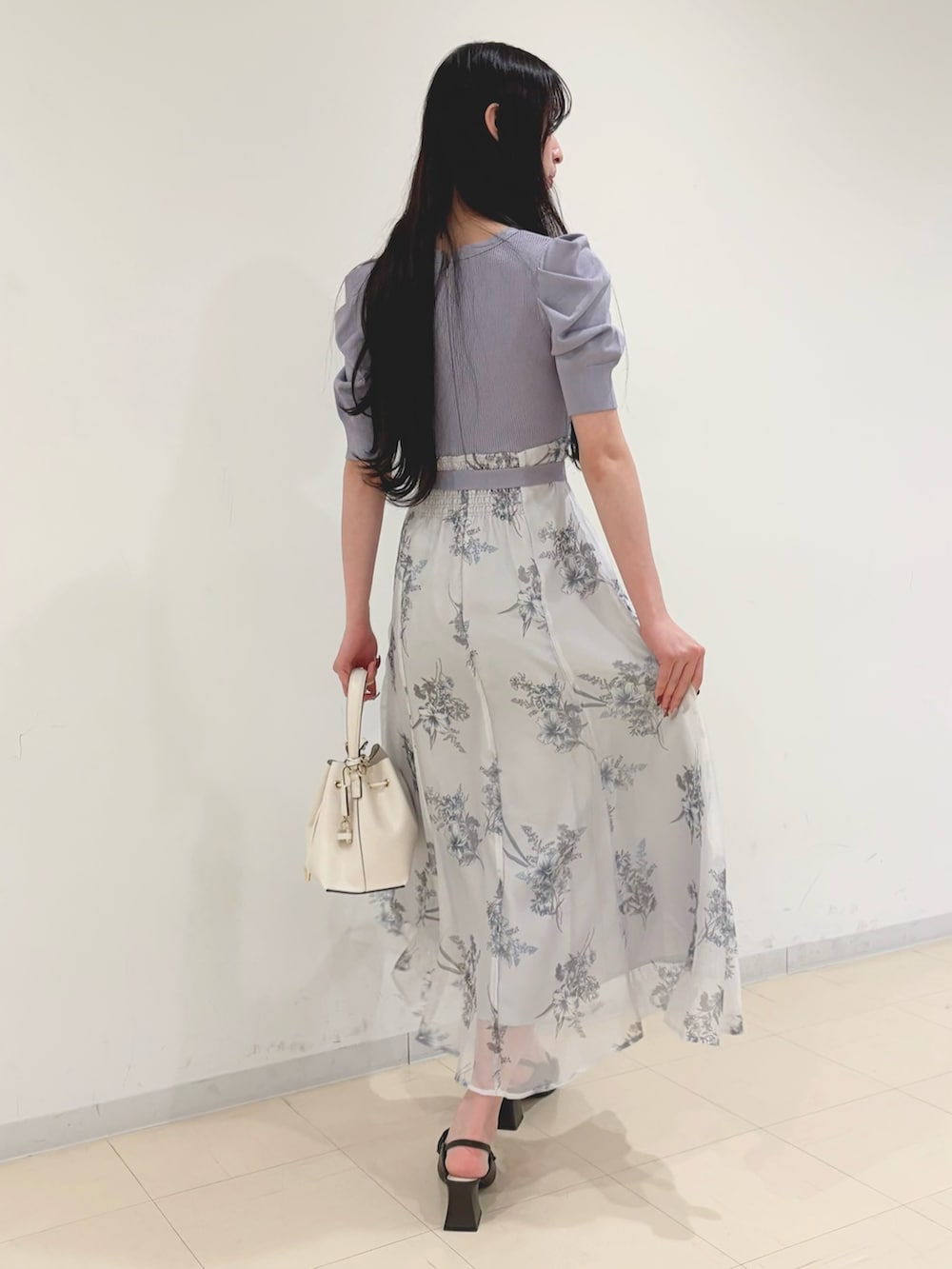 パープル系のワンピース、ホワイト系のショルダーバッグ、ブラウン系のパンプスを着用したレディースの冬コーディネートの3枚目の写真