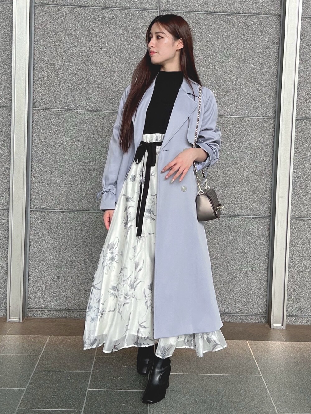 ブラック系のワンピース、ブルー系のトレンチコート、ブラウン系のハンドバッグを着用したレディースの秋コーディネートの2枚目の写真