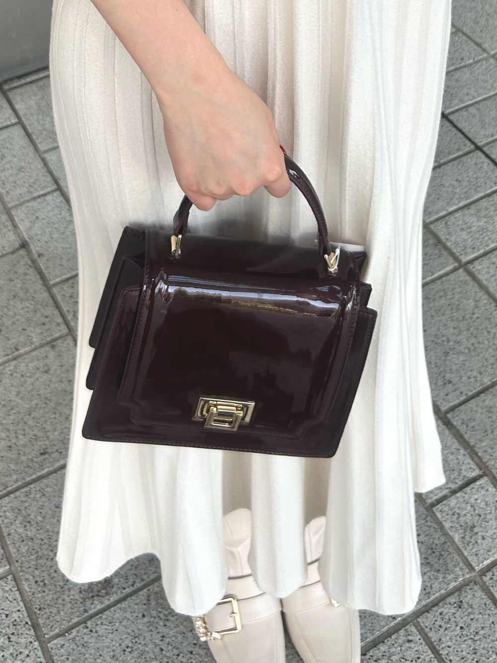 ホワイト系のワンピース、レッド系のハンドバッグ、ホワイト系のブーツを着用したレディースの冬コーディネートの4枚目の写真