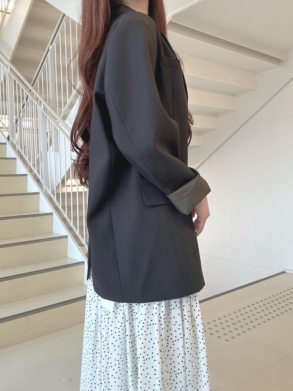 ブラック系のハンドバッグ、ホワイト系のパンプス、ブラウン系のテーラードジャケットを着用したレディースの秋コーディネートの7枚目の写真