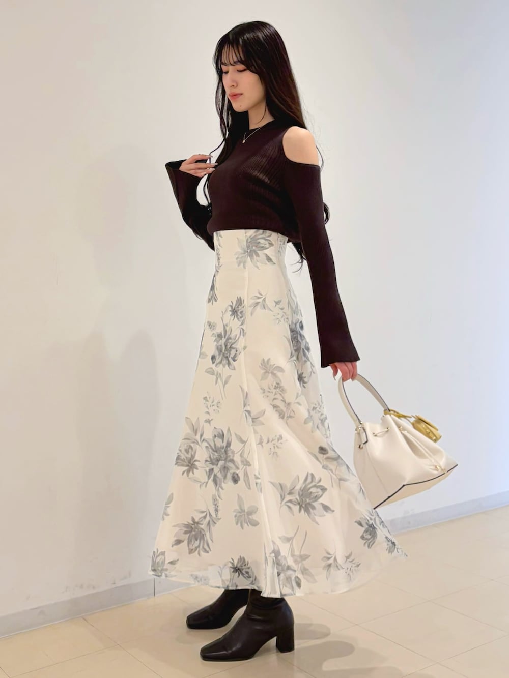 ホワイト系のスカート、ブラウン系のブーツ、ホワイト系のショルダーバッグを着用したレディースの冬コーディネートの2枚目の写真