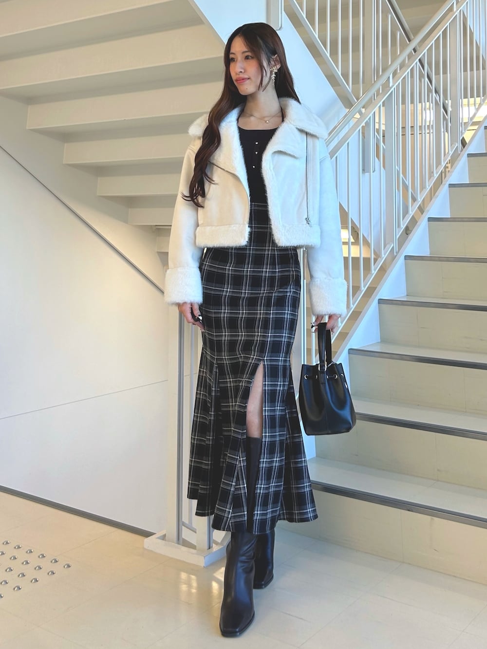 ブラック系のスカート、ホワイト系のムートンコート、ブラウン系のニット/セーターを着用したレディースの秋コーディネートの3枚目の写真