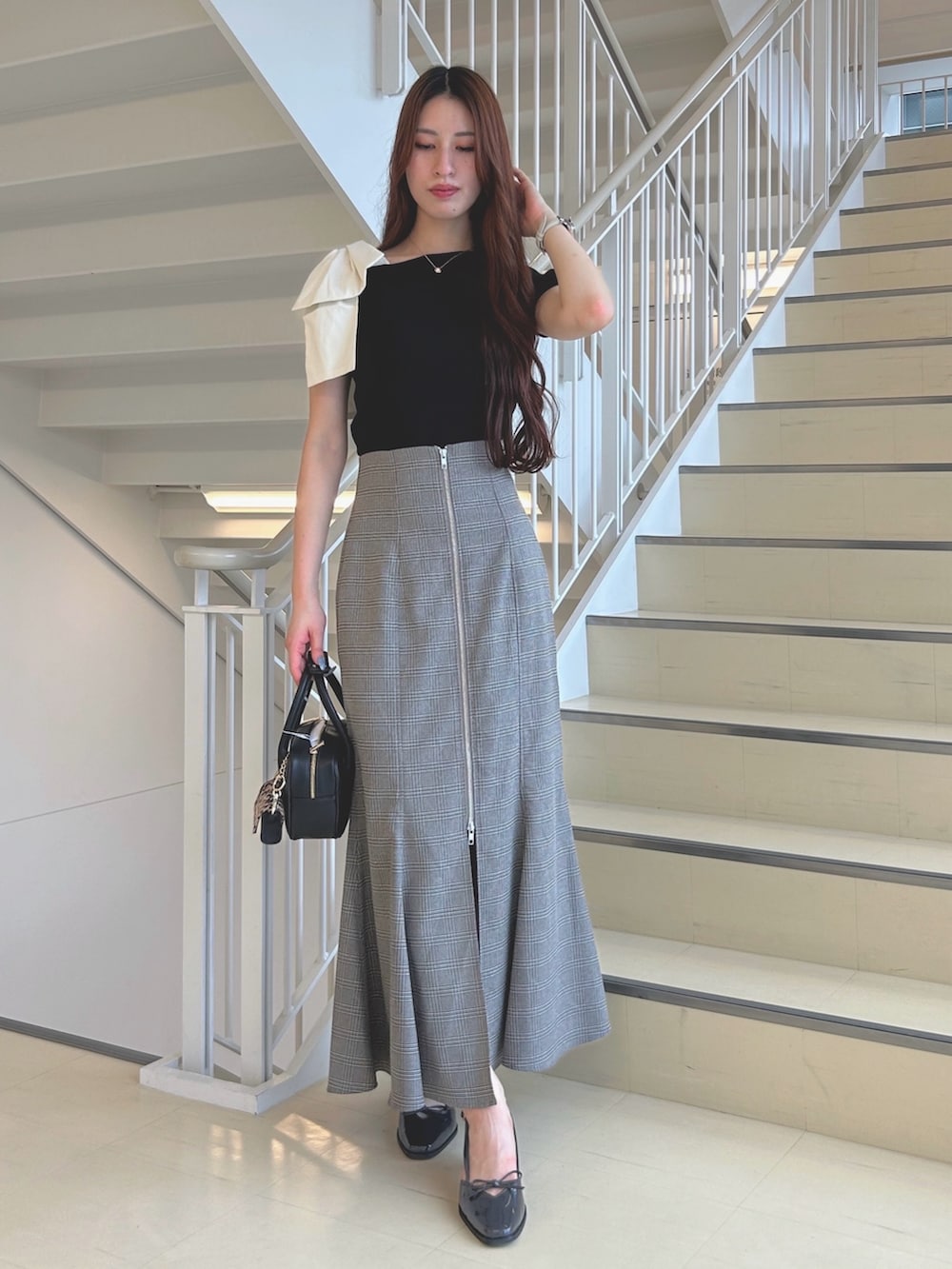 グレー系のパンプス、その他のスカート、ブラック系のニット/セーターを着用したレディースの夏コーディネートの3枚目の写真