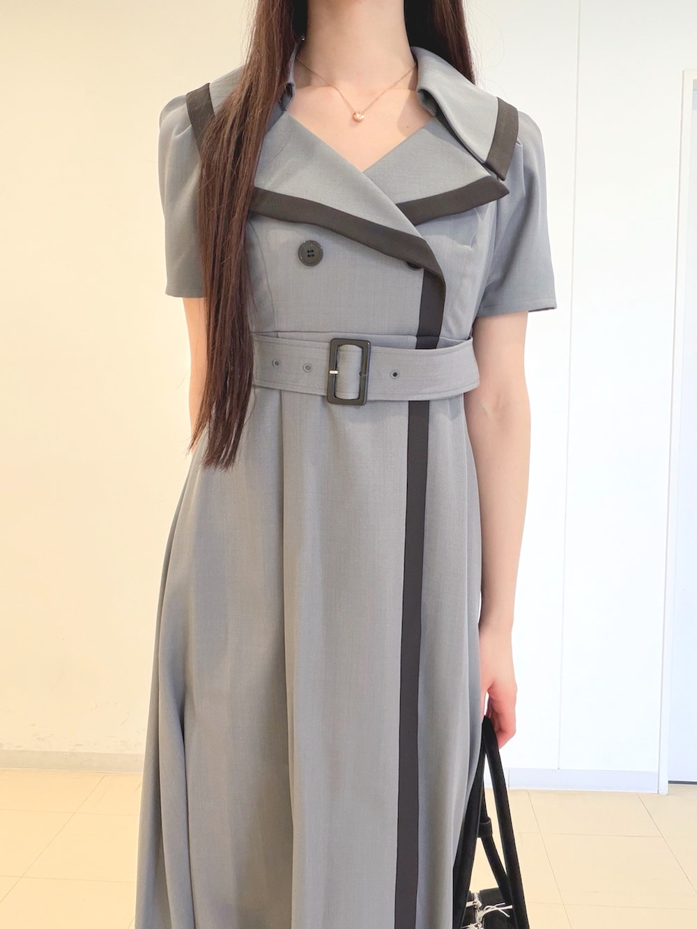 グレー系のワンピース、ブラック系のハンドバッグ、ホワイト系のパンプスを着用したレディースの春コーディネートの4枚目の写真