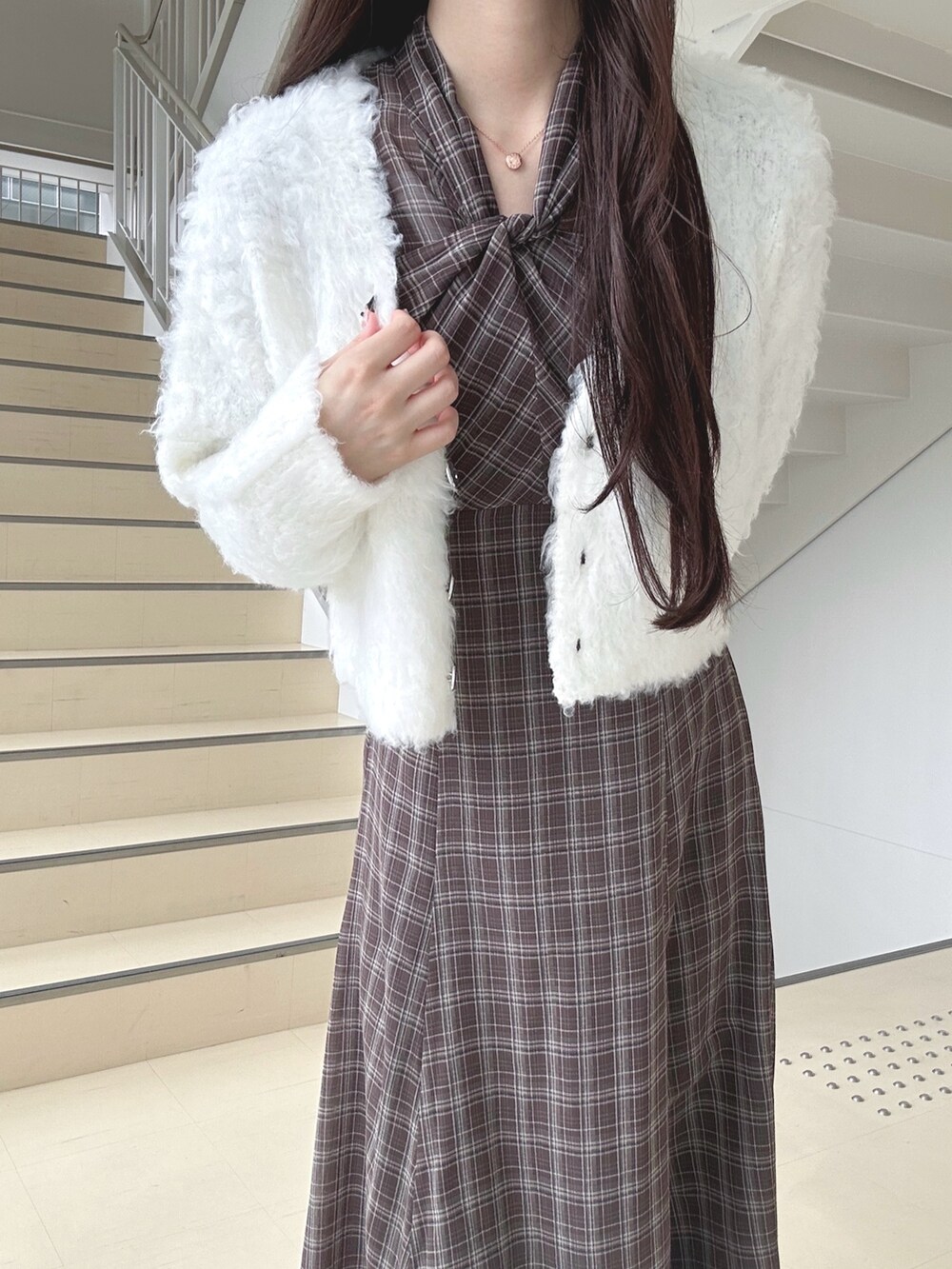 ブラウン系のワンピース、ホワイト系のハンドバッグ、ブラック系のブーツを着用したレディースの秋コーディネートの5枚目の写真