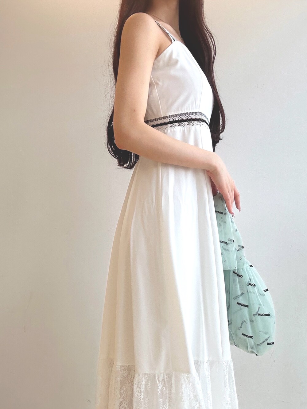 ホワイト系のワンピース、ブラウン系のサンダル、グリーン系のハンドバッグを着用したレディースの夏コーディネートの6枚目の写真