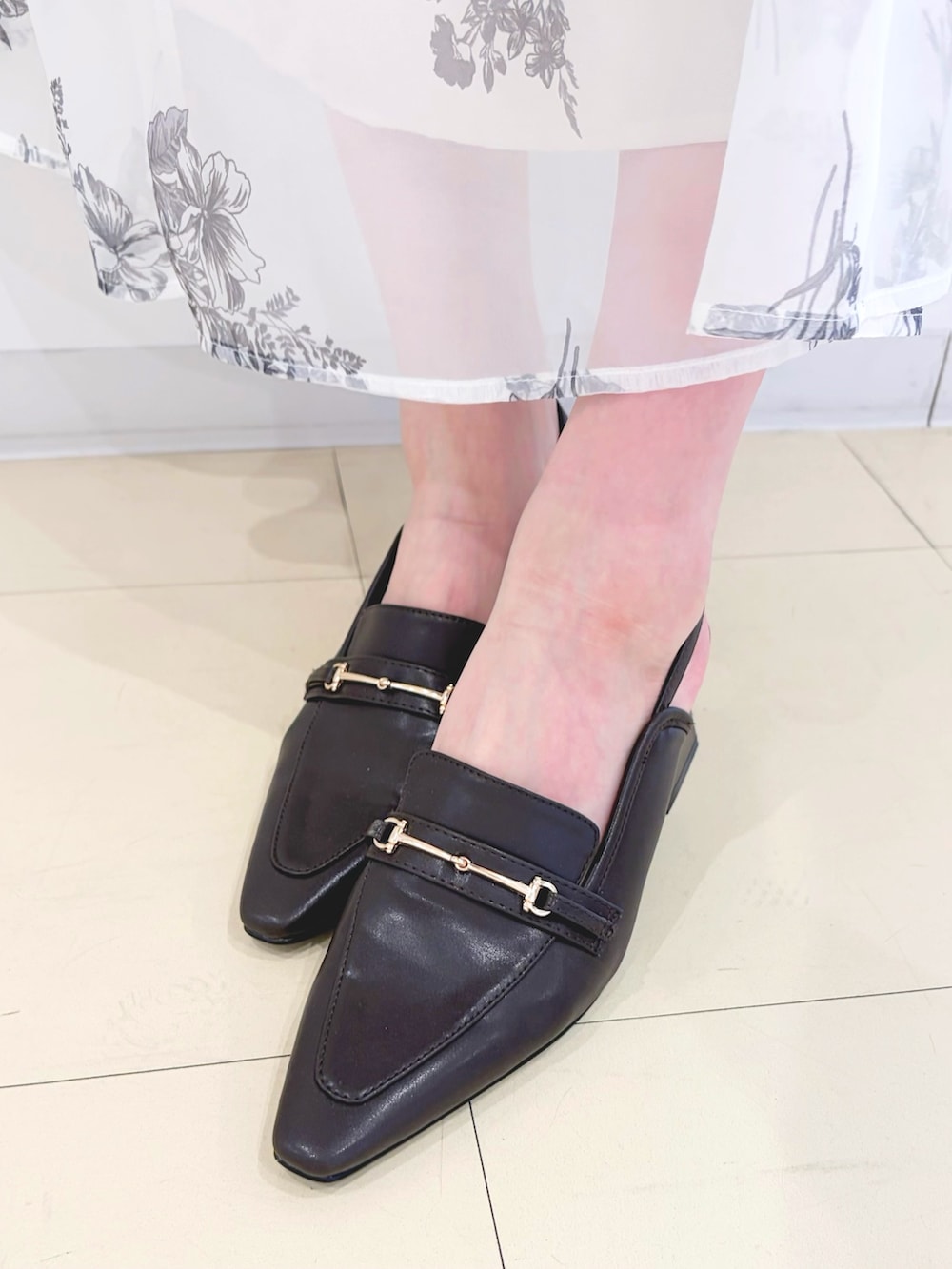 ブラック系のワンピース、ブラウン系のハンドバッグ、ブラウン系のパンプスを着用したレディースの春コーディネートの7枚目の写真