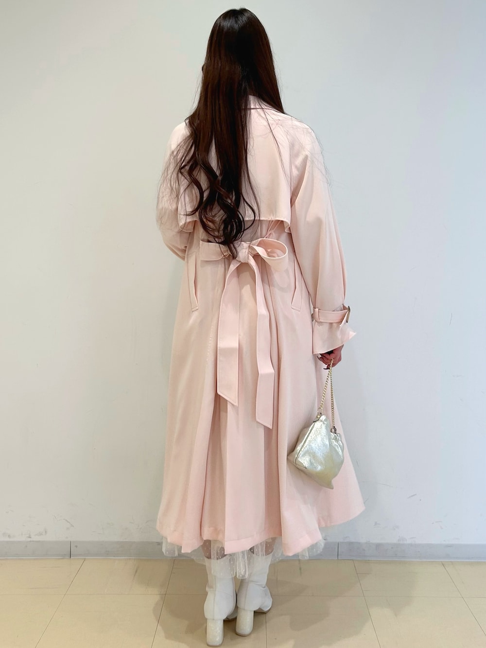 ホワイト系のワンピース、ピンク系のトレンチコート、ゴールド系のショルダーバッグを着用したレディースの冬コーディネートの3枚目の写真