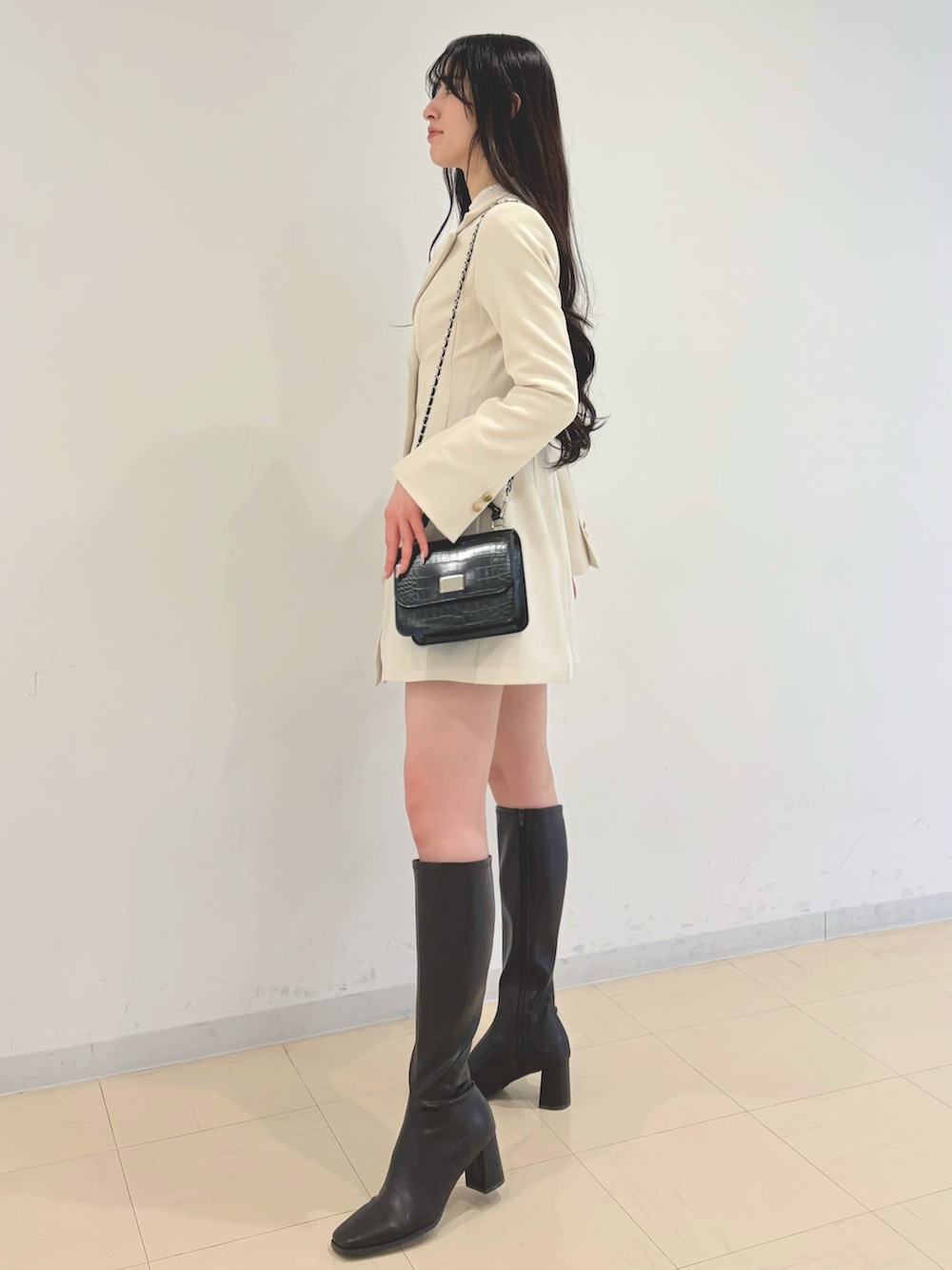 ホワイト系のワンピース、ホワイト系のニット/セーター、ブラック系のハンドバッグを着用したレディースの冬コーディネートの2枚目の写真