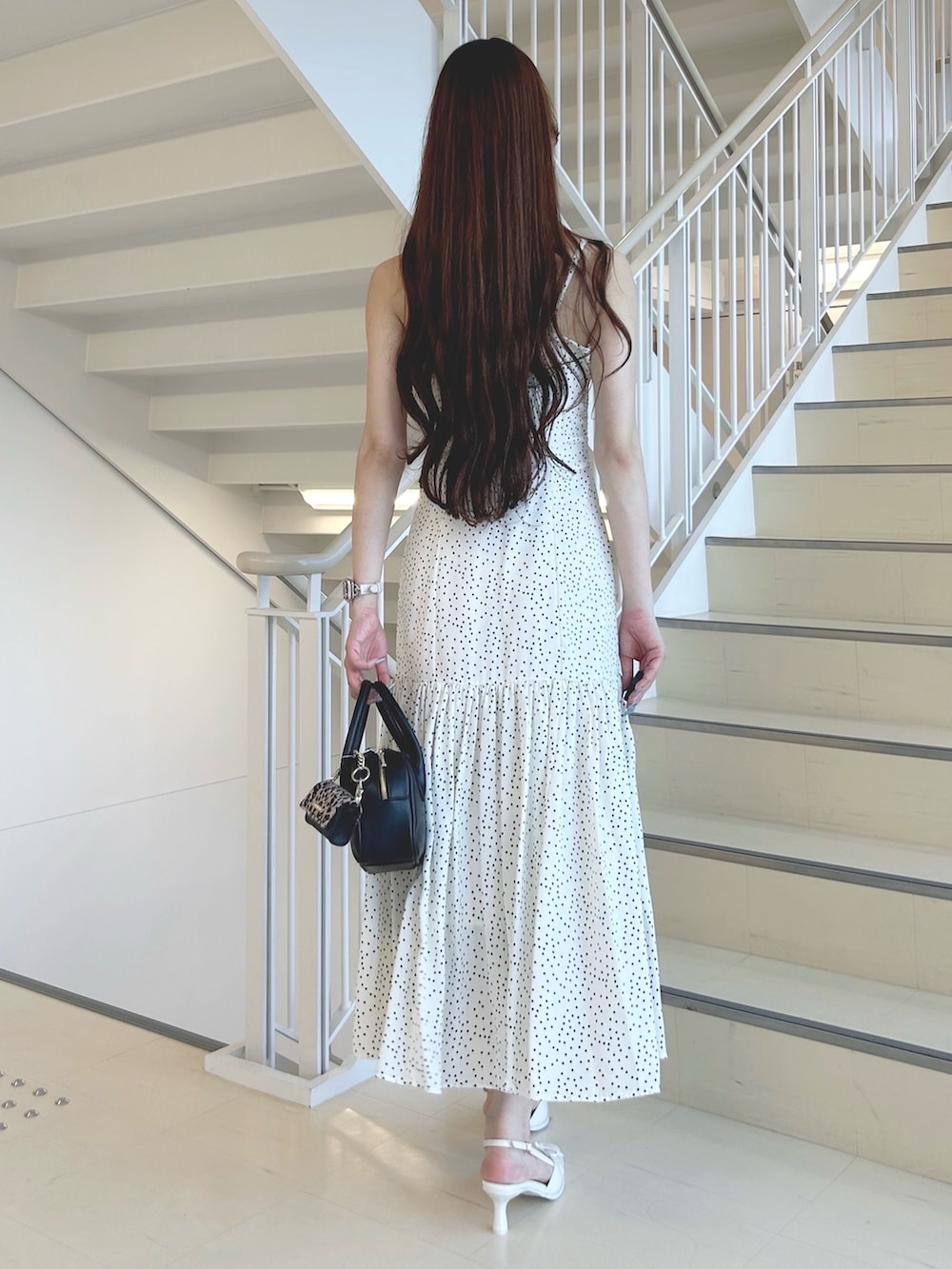 ホワイト系のパンプス、ブラック系のハンドバッグ、ホワイト系のワンピースを着用したレディースの秋コーディネートの4枚目の写真