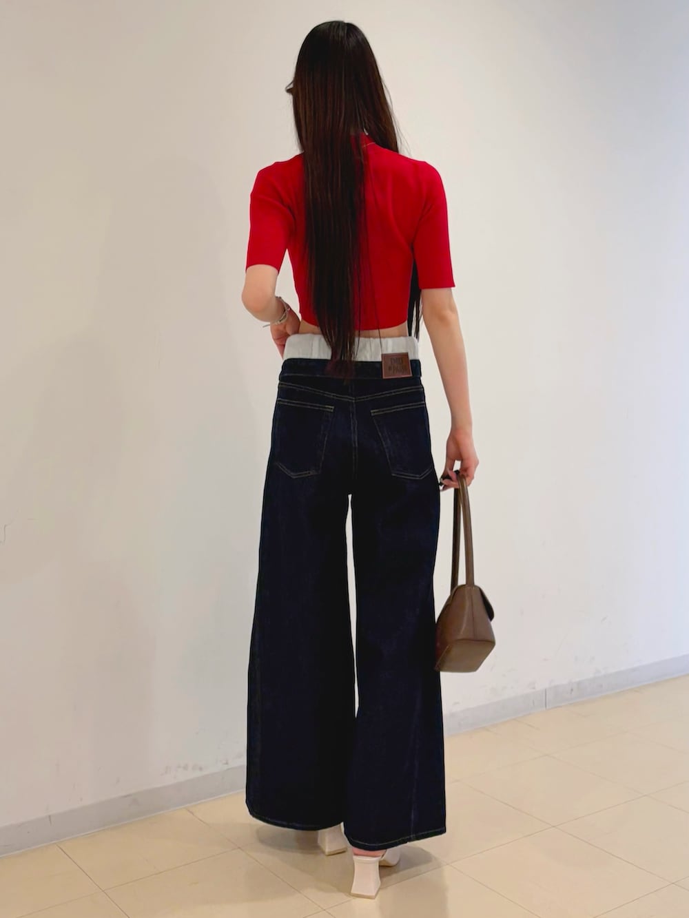 ブルー系のその他パンツ、レッド系のニット/セーター、ブラウン系のハンドバッグを着用したレディースの春コーディネートの5枚目の写真