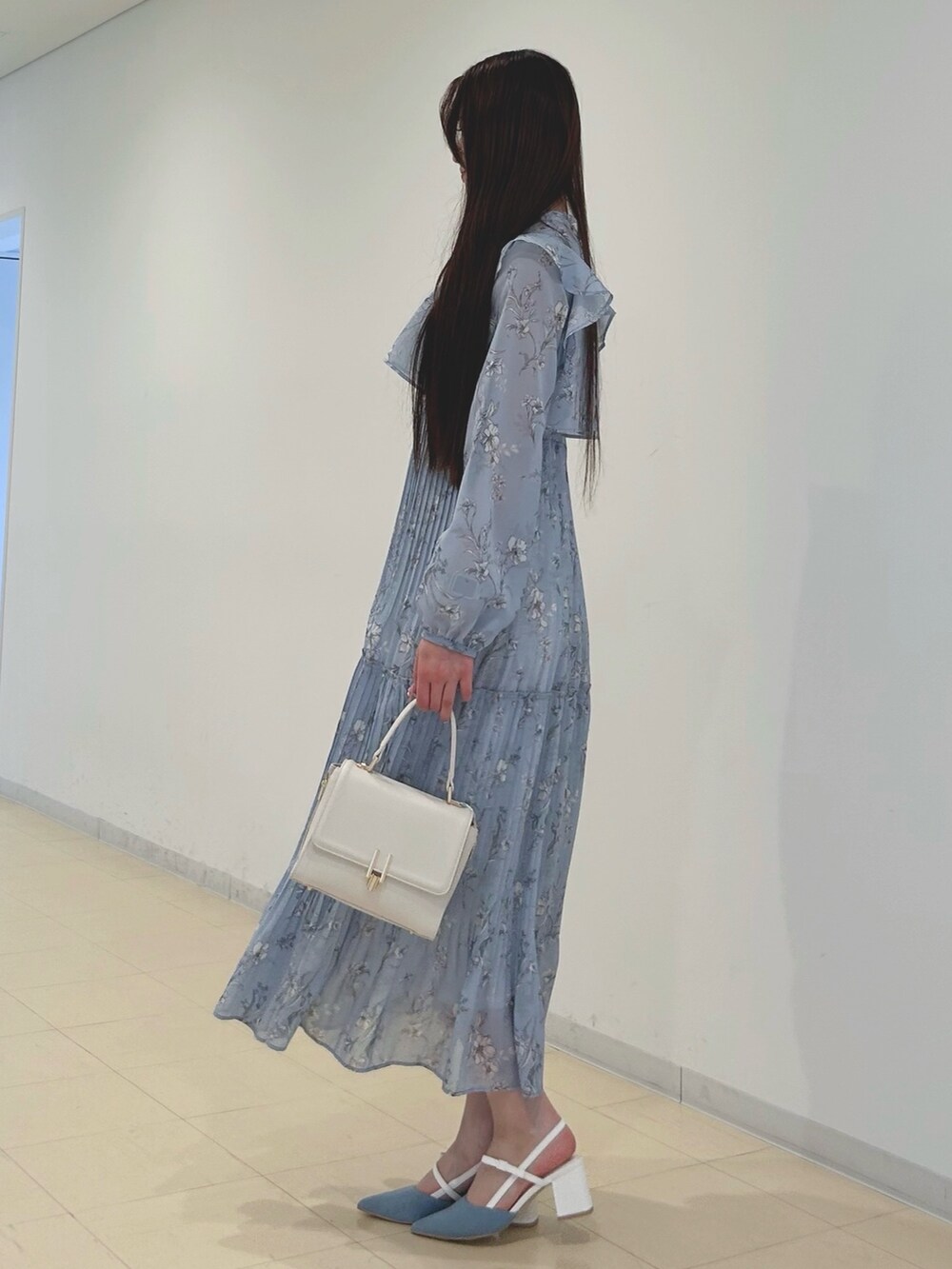 ブルー系のワンピース、ホワイト系のパンプス、ホワイト系のハンドバッグを着用したレディースの春コーディネートの2枚目の写真