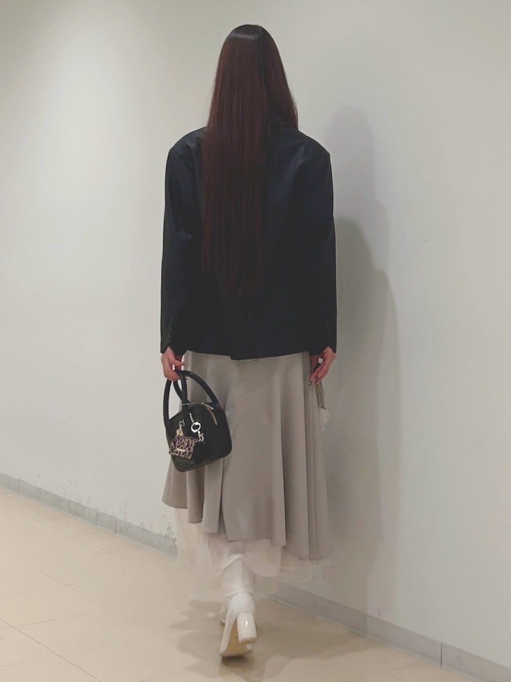 ベージュ系のスカート、グレー系のニット/セーター、ブラック系のハンドバッグを着用したレディースの秋コーディネートの4枚目の写真