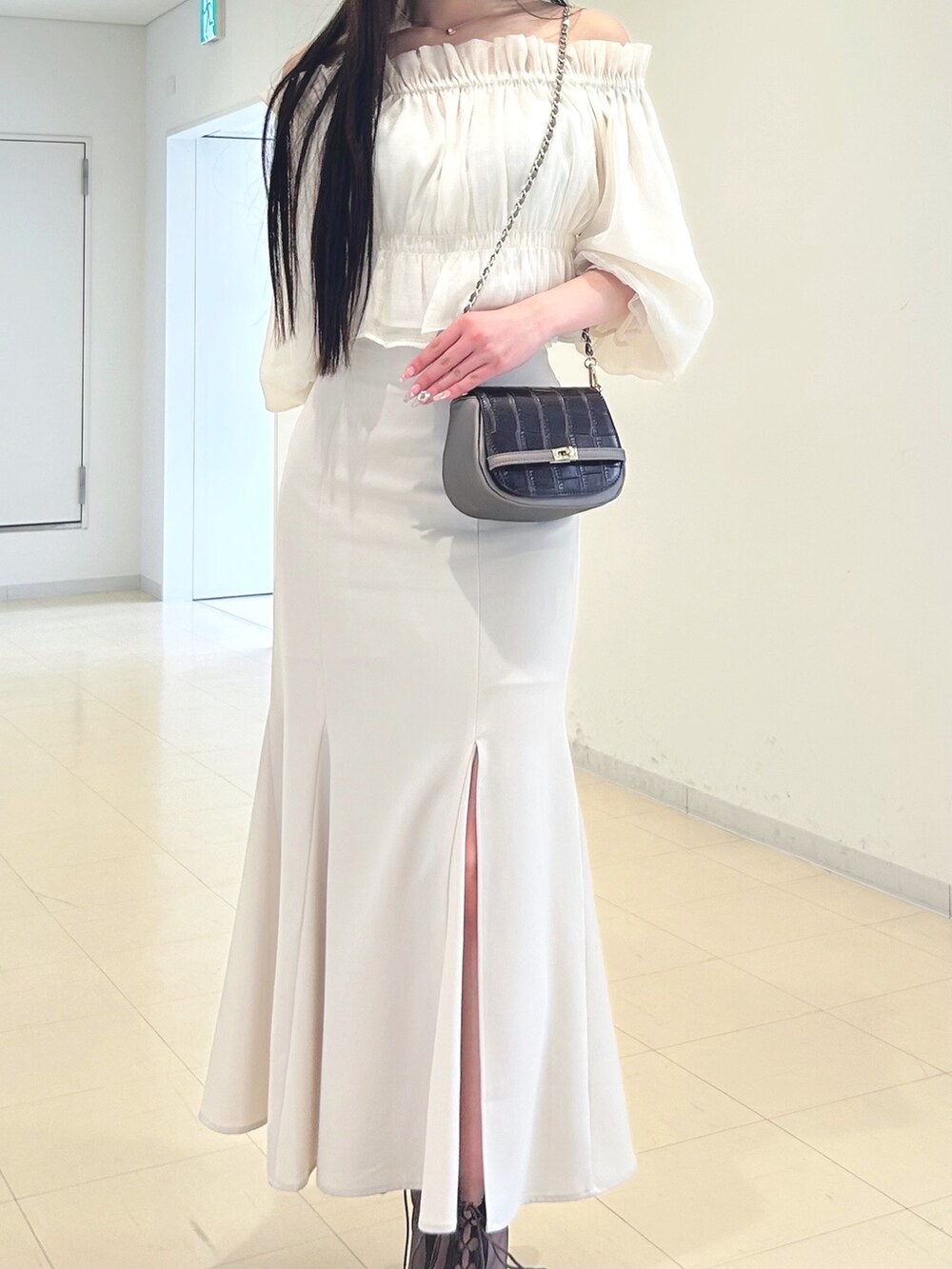 ホワイト系のスカート、ベージュ系のノーカラージャケット、ブラウン系のハンドバッグを着用したレディースの春コーディネートの6枚目の写真