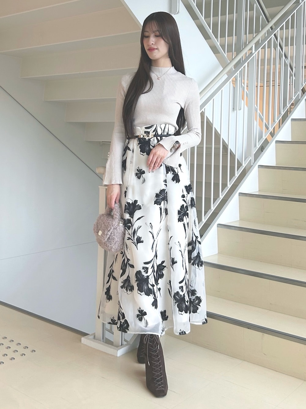 ホワイト系のスカート、ベージュ系のニット/セーター、ピンク系のハンドバッグを着用したレディースの秋コーディネートの3枚目の写真