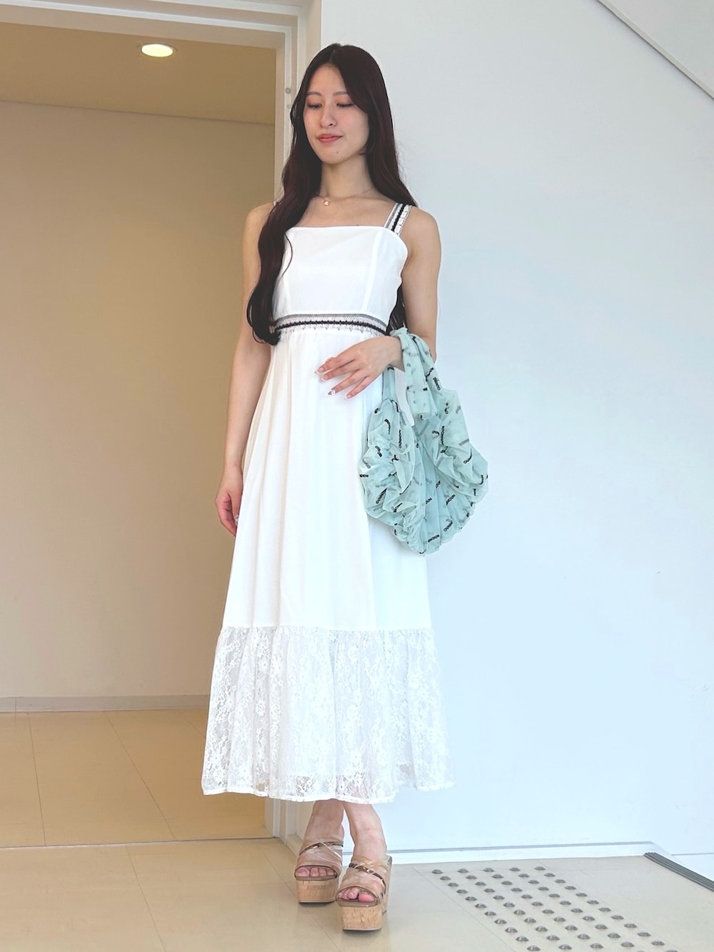 ホワイト系のワンピース、ブラウン系のサンダル、グリーン系のハンドバッグを着用したレディースの夏コーディネートの3枚目の写真