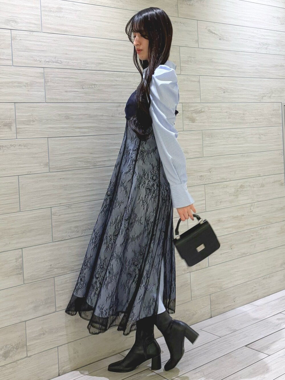 ブルー系のワンピース、ブラック系のハンドバッグ、ブラック系のブーツを着用したレディースの冬コーディネートの2枚目の写真