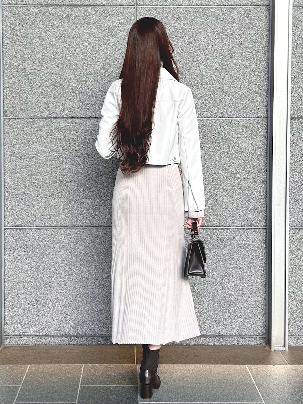 ブラウン系のハンドバッグ、ホワイト系のライダースジャケット、ピンク系のワンピースを着用したレディースの冬コーディネートの4枚目の写真