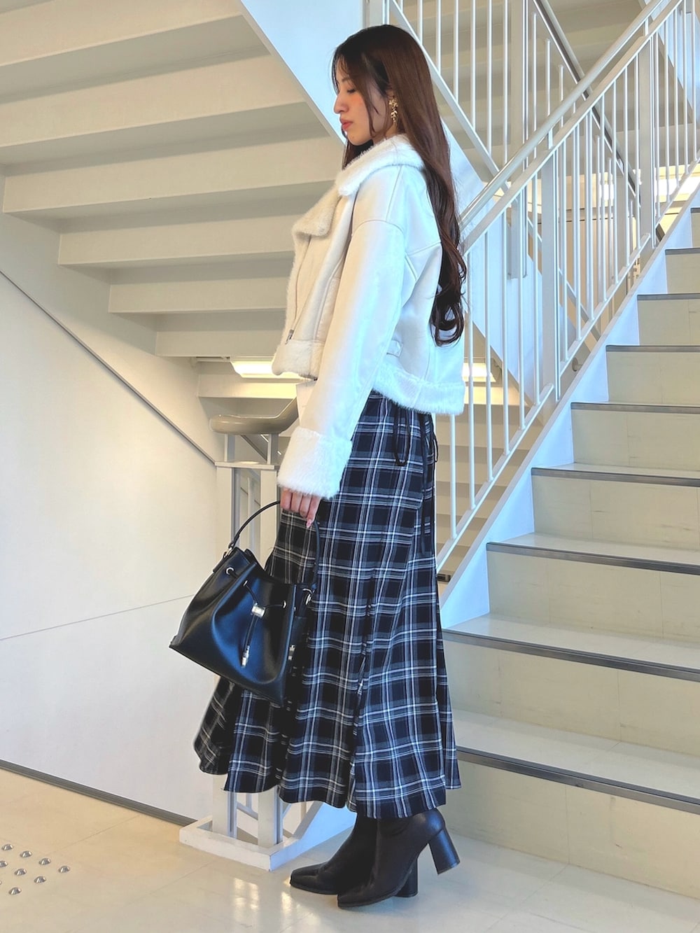 ブラック系のスカート、ホワイト系のムートンコート、ブラウン系のニット/セーターを着用したレディースの秋コーディネートの2枚目の写真