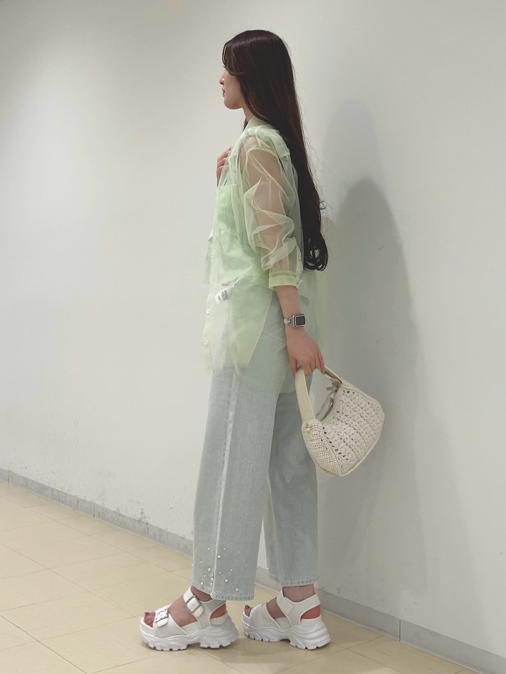 ブルー系のデニムパンツ、グリーン系のシャツ/ブラウス、ホワイト系のショルダーバッグを着用したレディースの春コーディネートの2枚目の写真