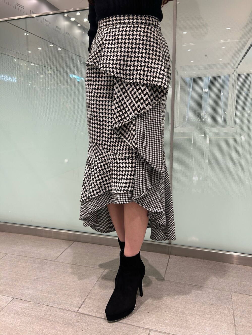 ブラック系のニット/セーター、ブラック系のブーツ、その他のスカートを着用したレディースの冬コーディネートの7枚目の写真