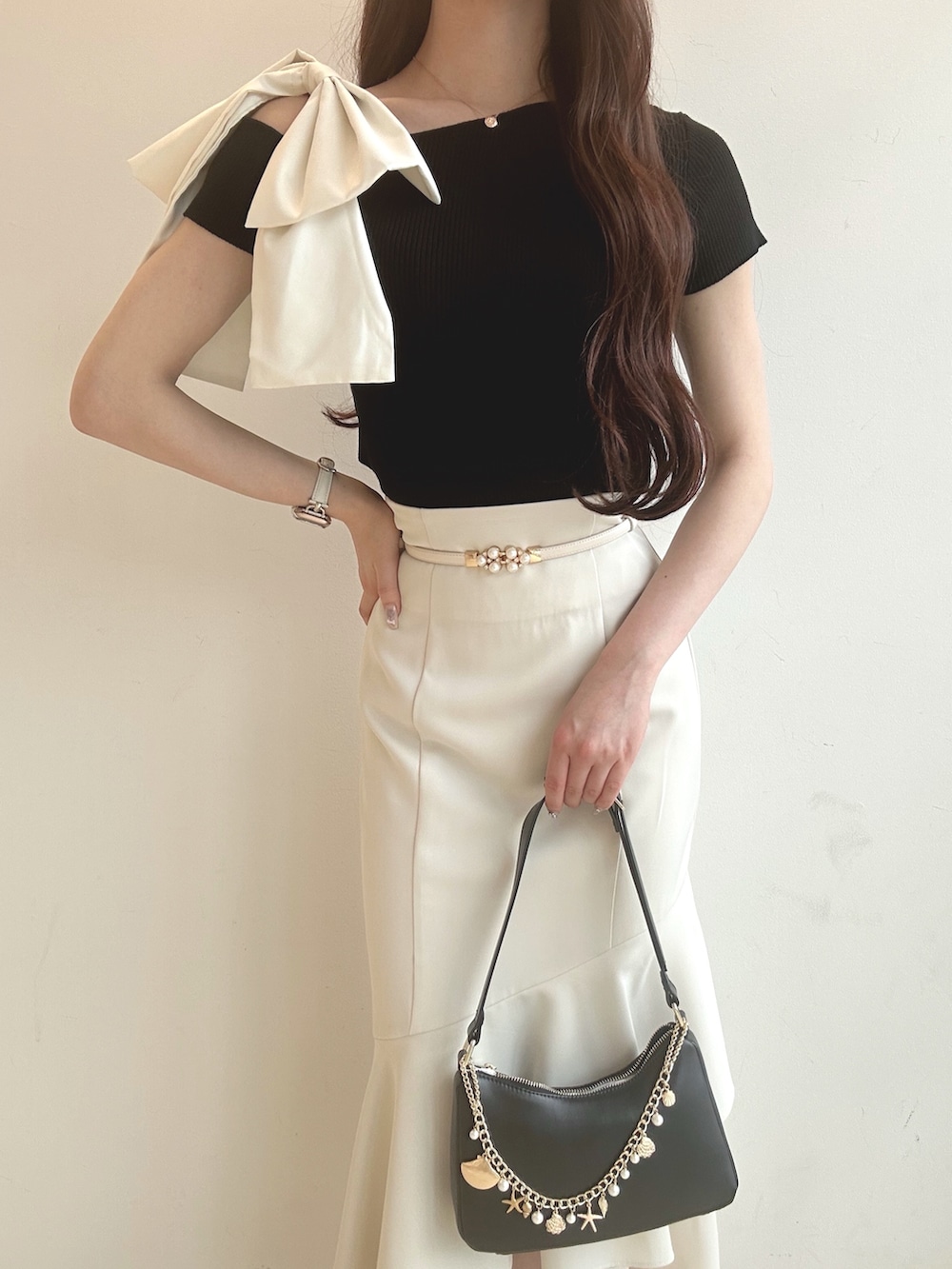 ブラック系のニット/セーター、ブラック系のハンドバッグ、ホワイト系のサンダルを着用したレディースの夏コーディネートの5枚目の写真