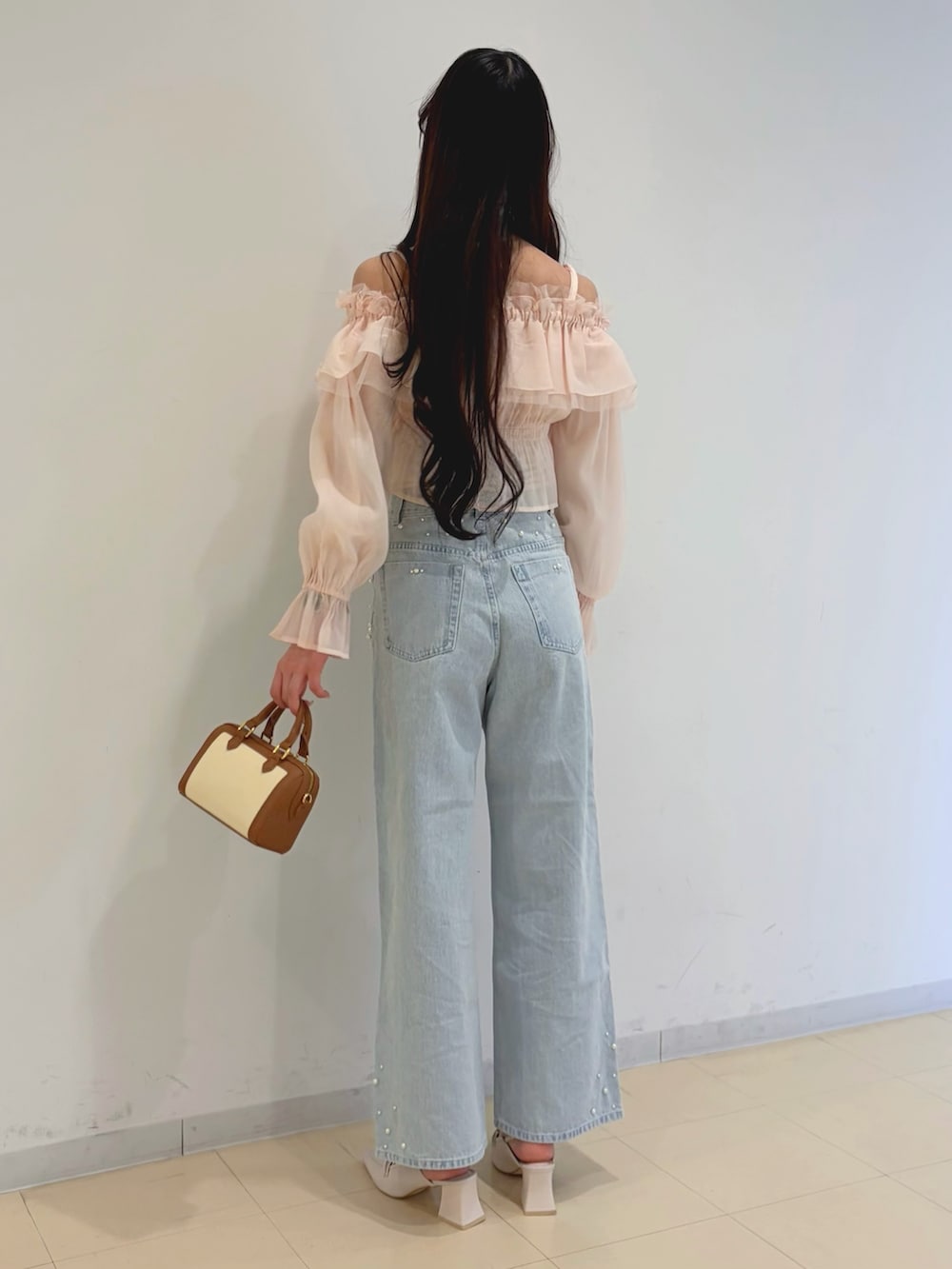 ピンク系のシャツ/ブラウス、ブルー系のデニムパンツ、ブラウン系のハンドバッグを着用したレディースの春コーディネートの3枚目の写真